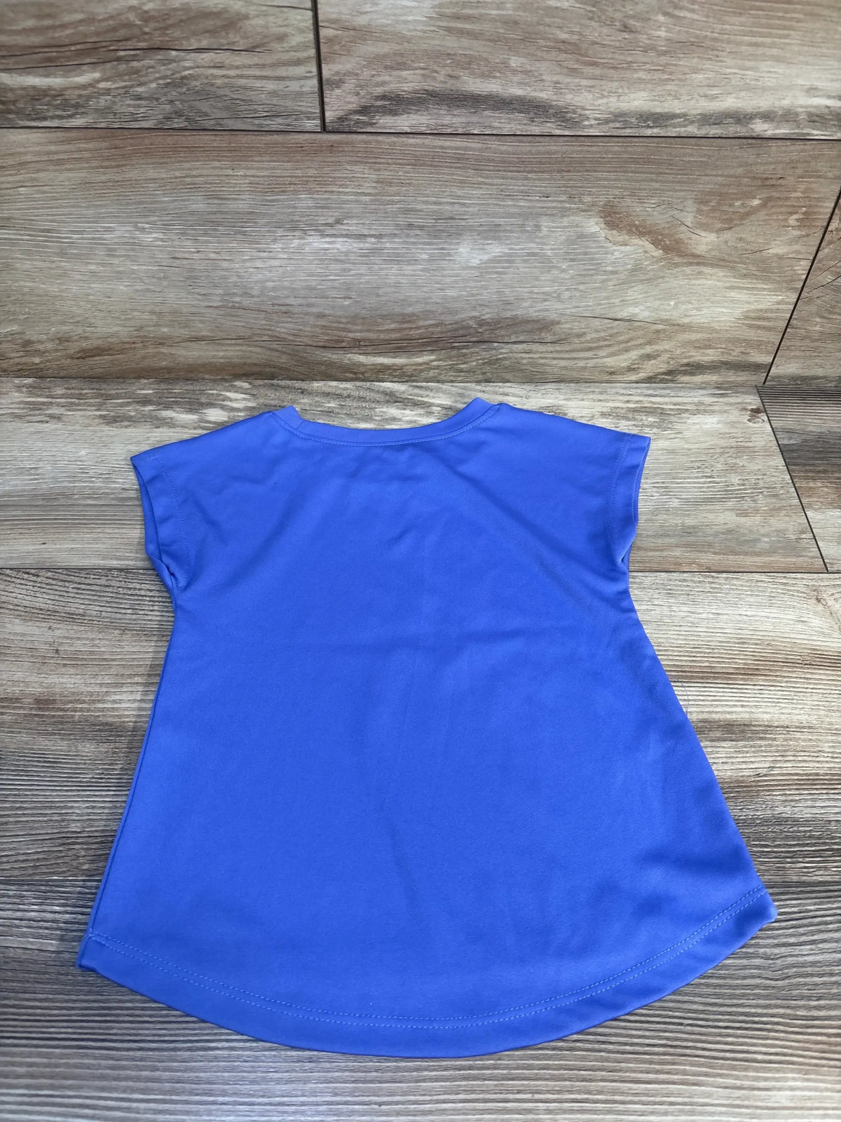 Back view of lilac Okie Dokie Active Soccer toddler shirt (2T) showing short cap sleeves and curved hem on wood floor