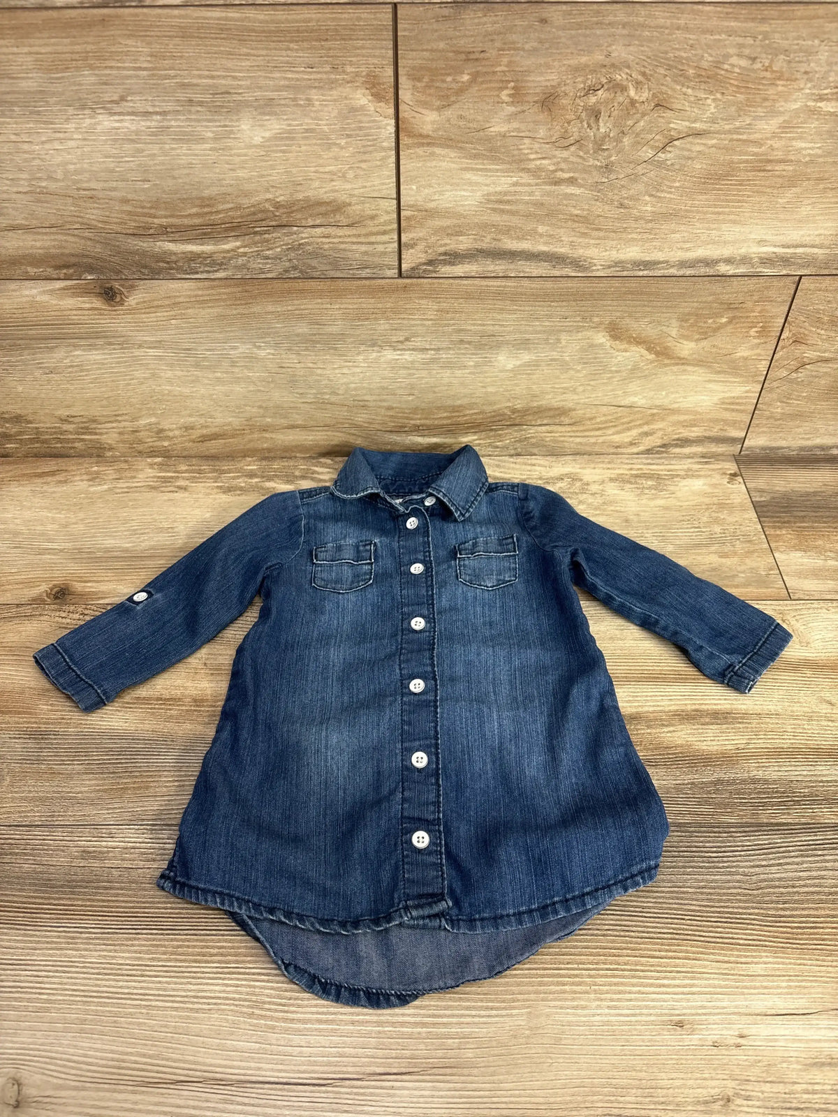Long sleeve denim button-down toddler dress with chest pockets on wood background