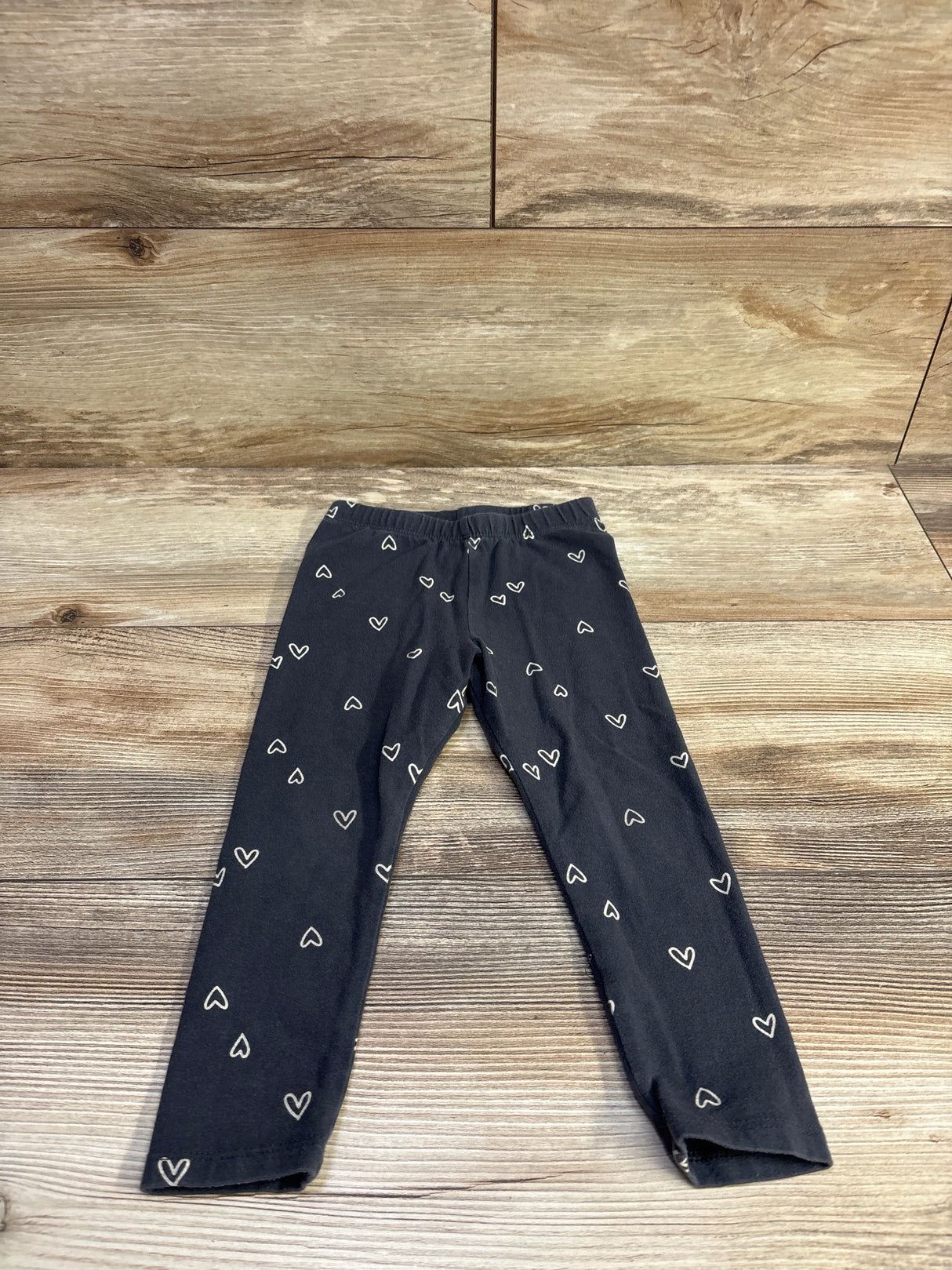 Flat lay of Cat & Jack toddler grey leggings with white heart print on wood background
