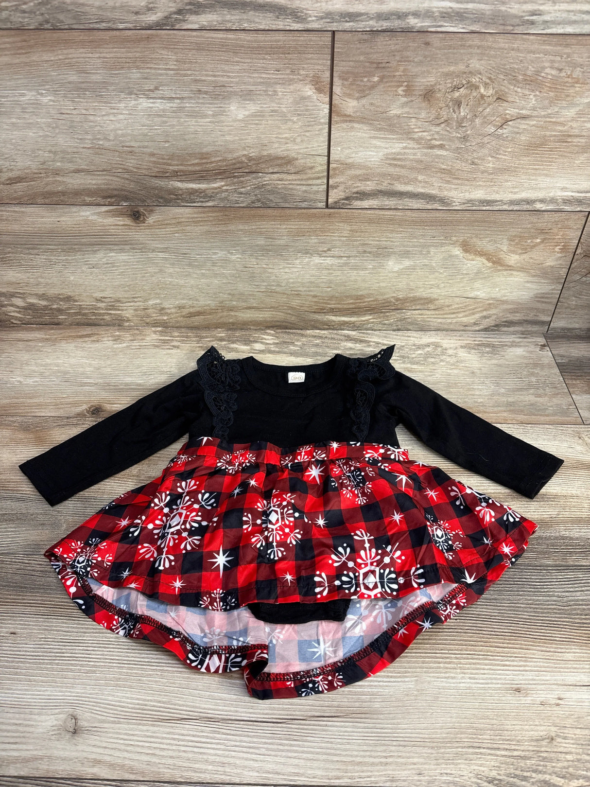 Toddler long sleeve dress with black lace top and red plaid snowflake skirt on wood floor