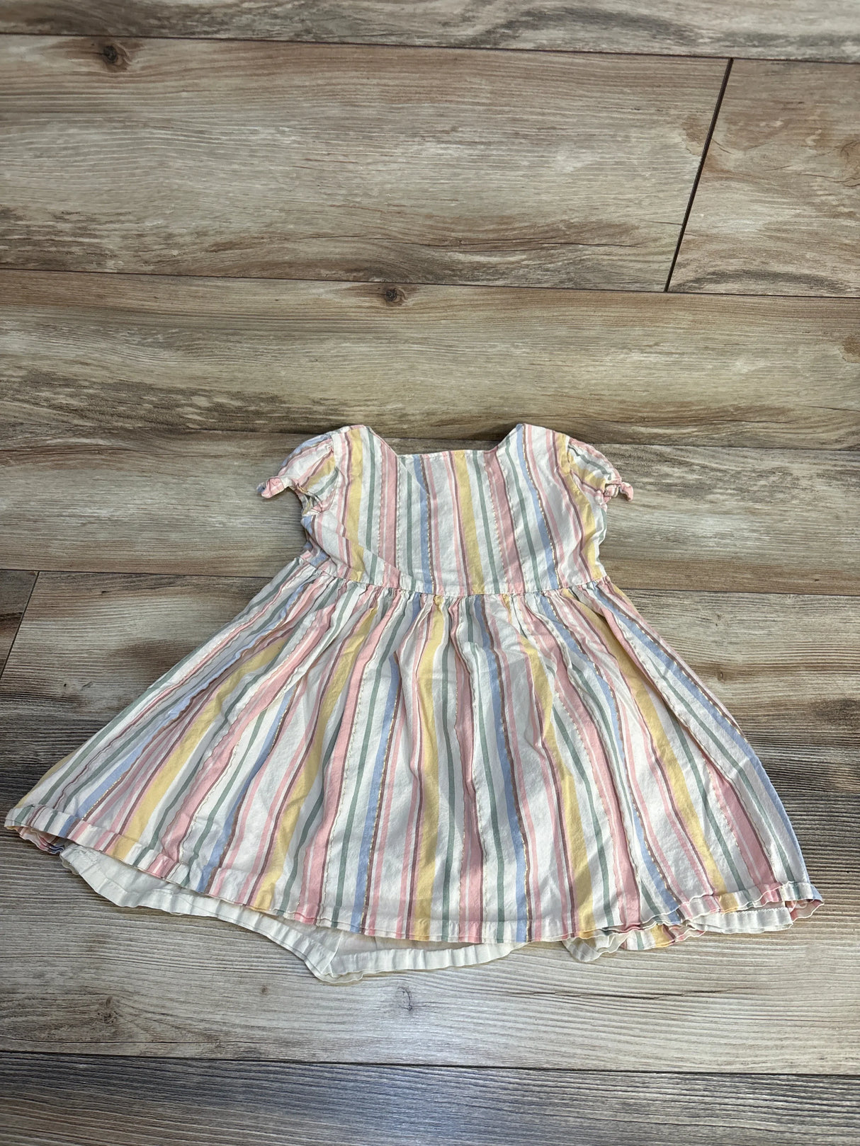Pastel striped short sleeve toddler dress on wooden floor, gently used kids clothing