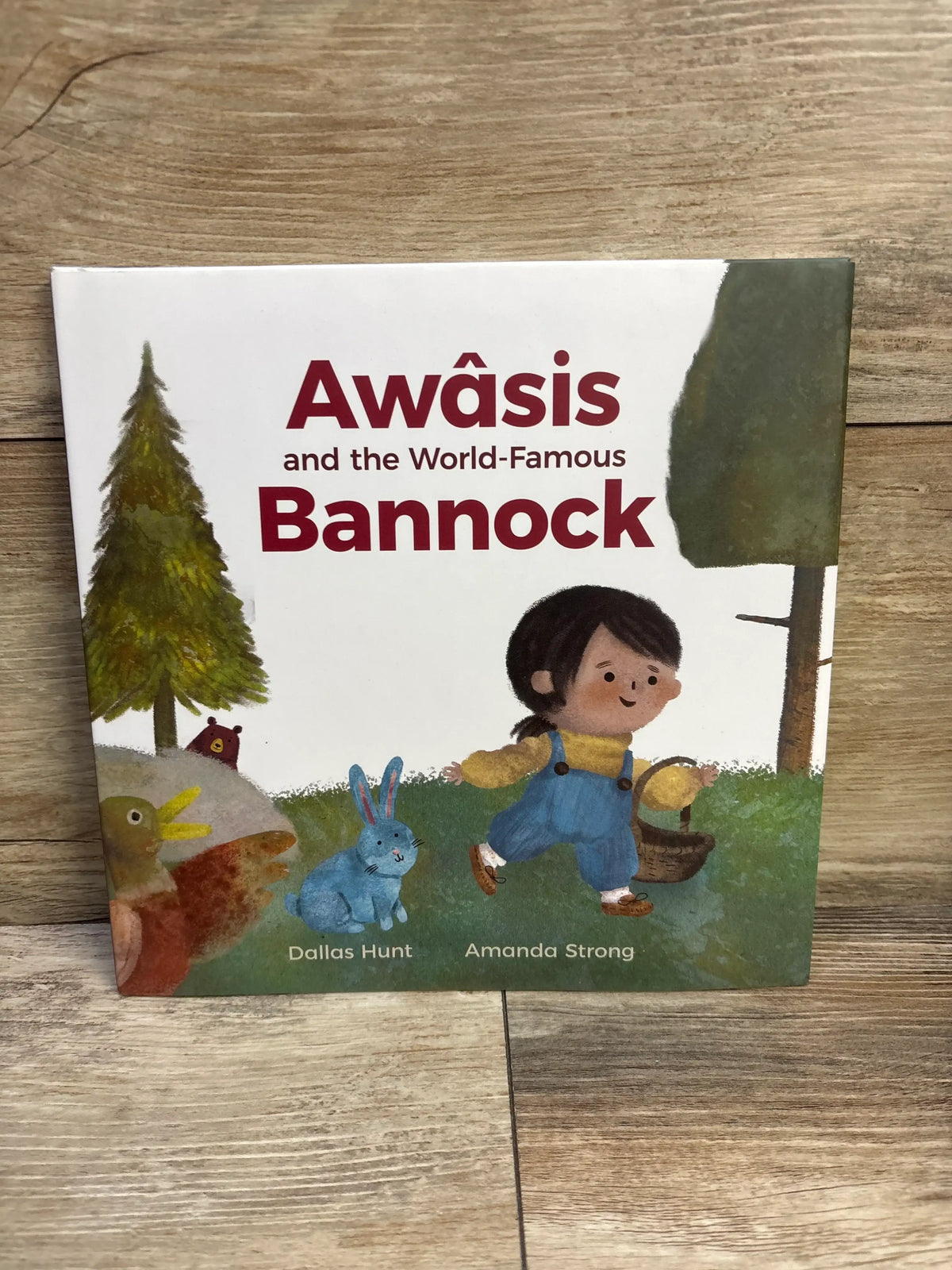 Front view of Awâsis and the World-Famous Bannock hardcover book showcasing an illustrated cover on a wood surface