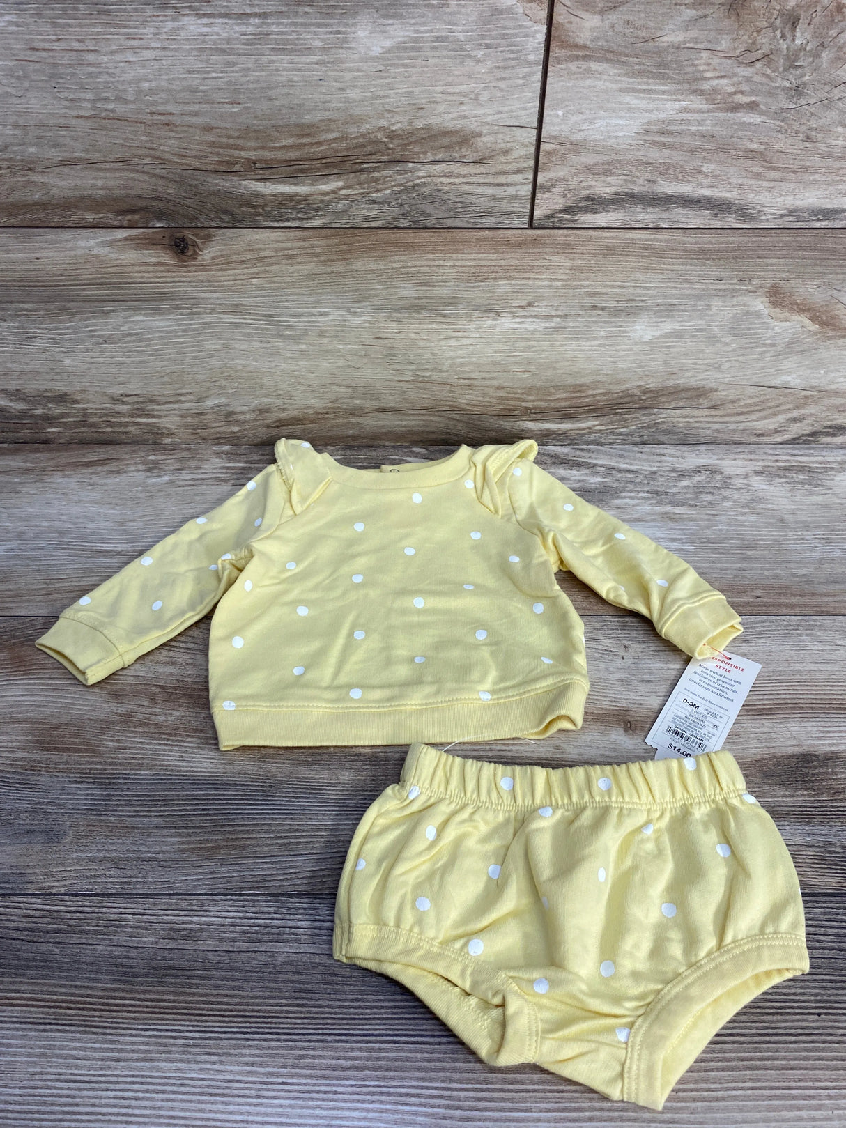 Yellow baby outfit with white polka dots, long-sleeve shirt and matching shorts on wooden floor