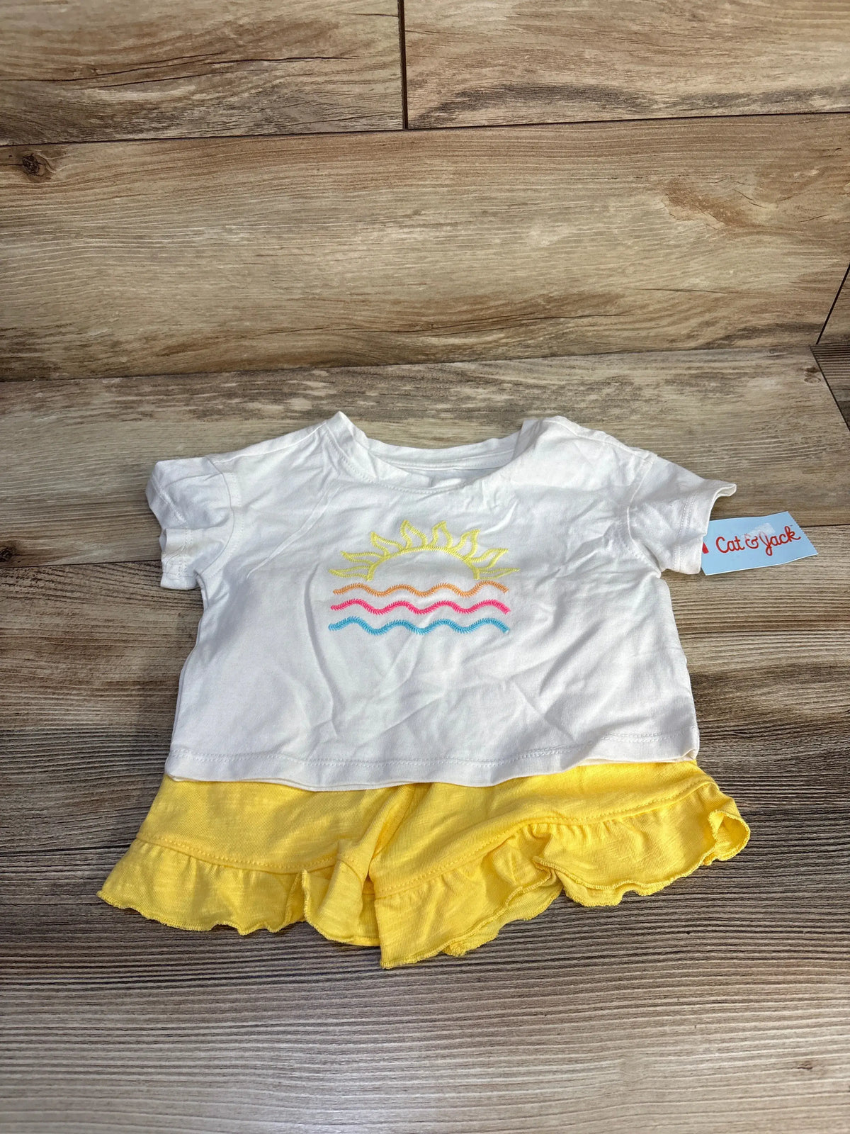 Front view of Cat and Jack 2-piece sun and waves T-shirt and shorts set showcasing white shirt and yellow ruffled shorts