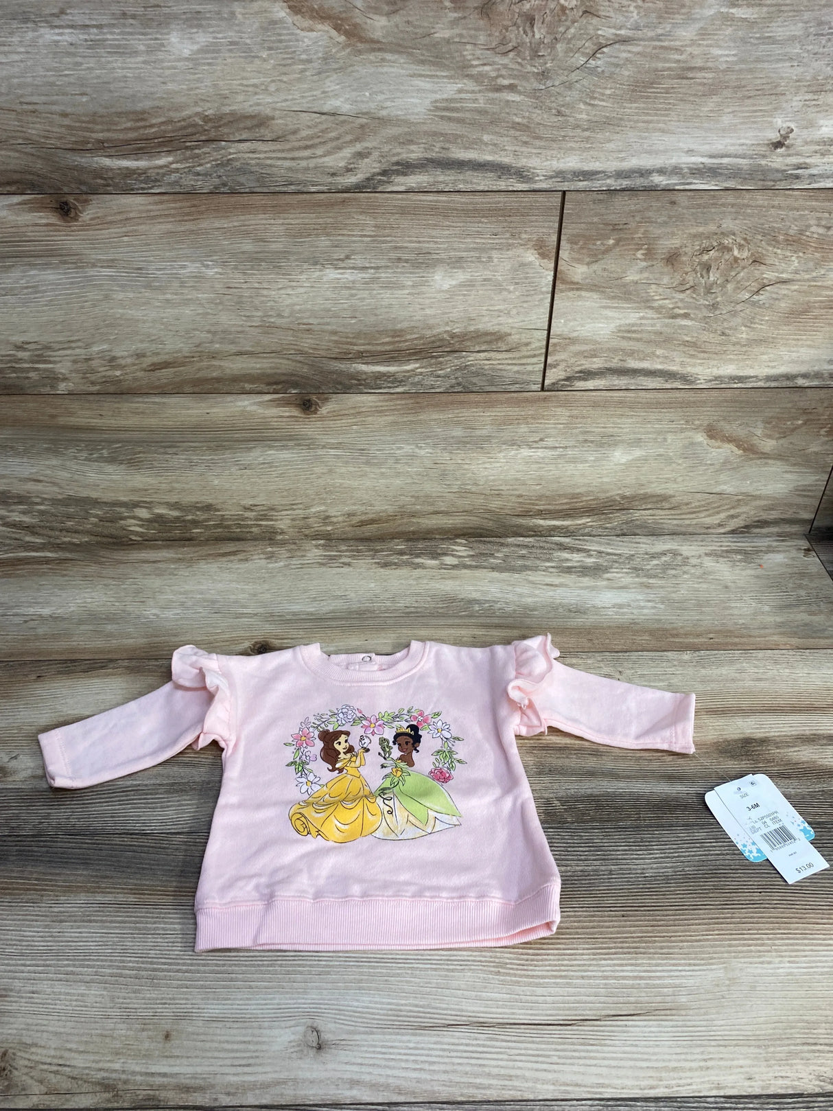 Pink long sleeve toddler shirt with cartoon princess print on wood background