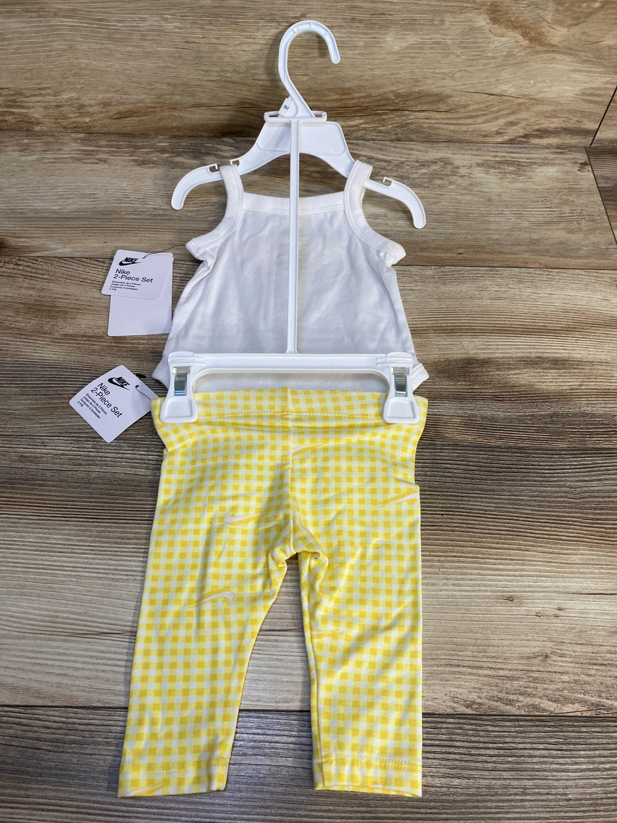 Baby girl white tank top and yellow checkered leggings set on wood background