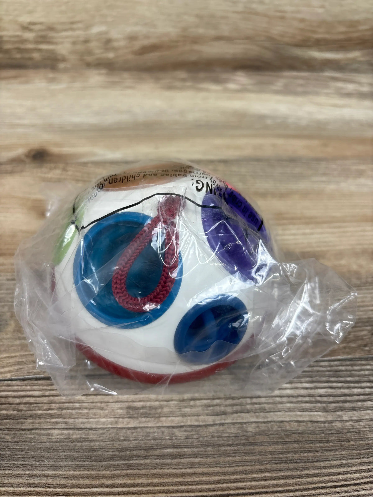 Front view of HahaLand Montessori sensory pop fidget spinning toy showing colorful sections and red braided cord in clear packaging