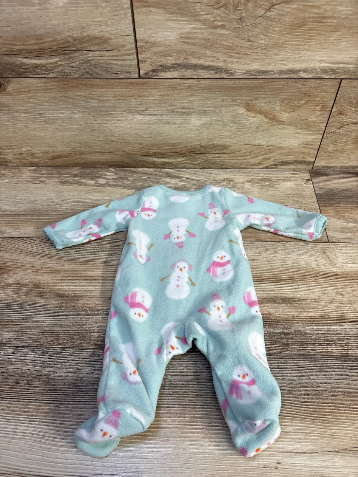 Front view of blue Just One You snowman blanket sleeper with long sleeves, footed legs, and snowman print on wood floor