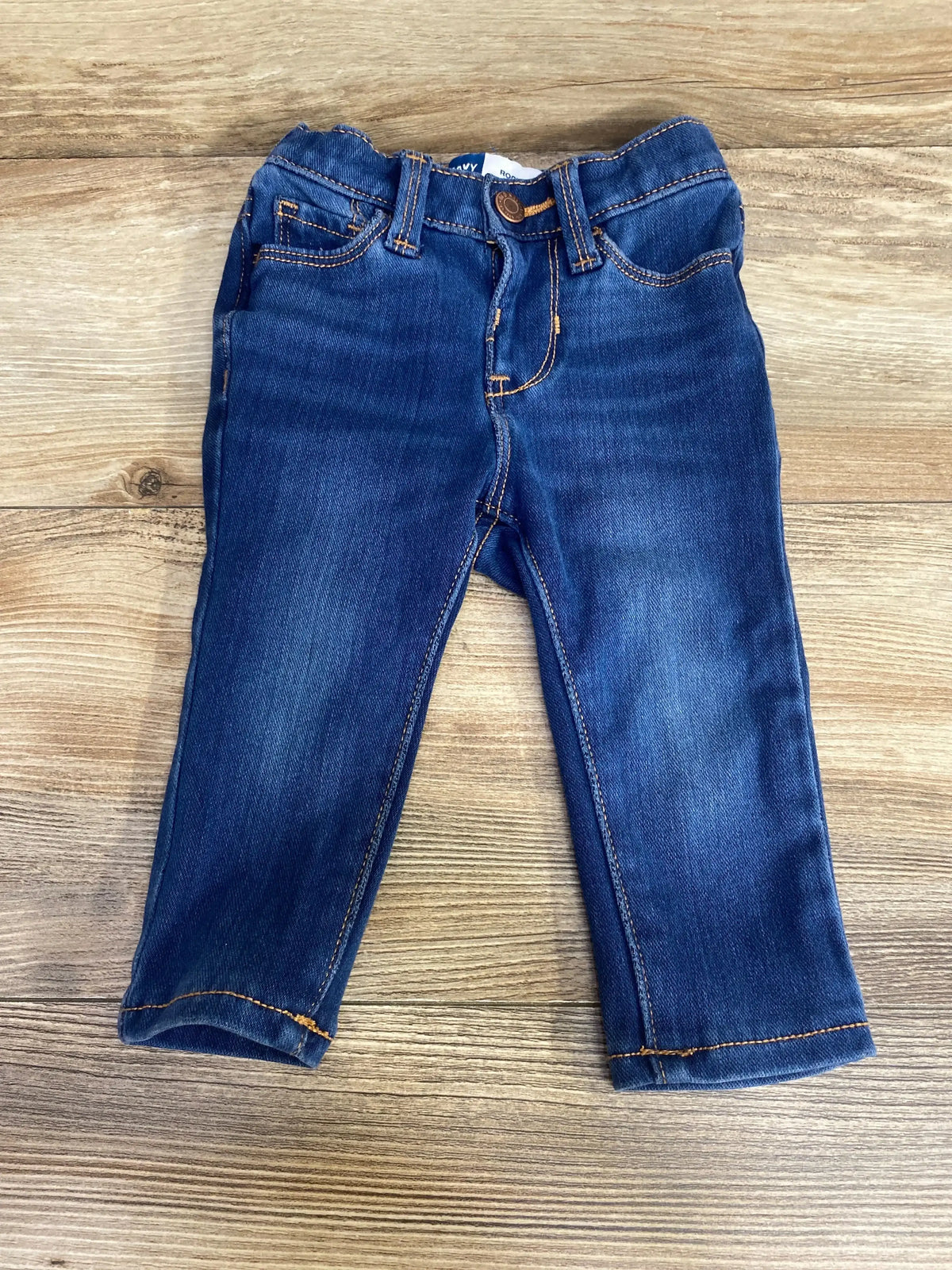 Front view of toddler blue Old Navy Rockstar jeggings showing elastic waist, faux pockets on wood background