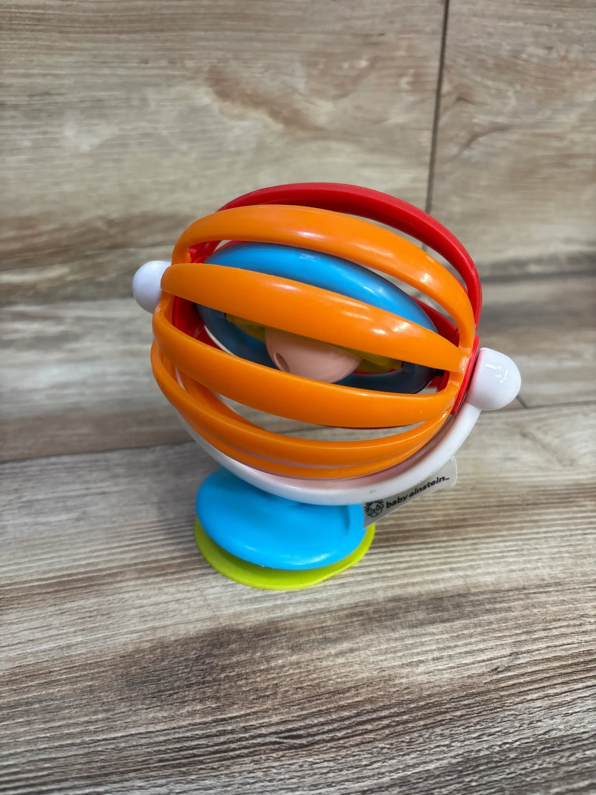 Angled view of Baby Einstein Sticky Spinner High Chair Toy showcasing colorful spinning loops and suction cup on a wooden tabletop