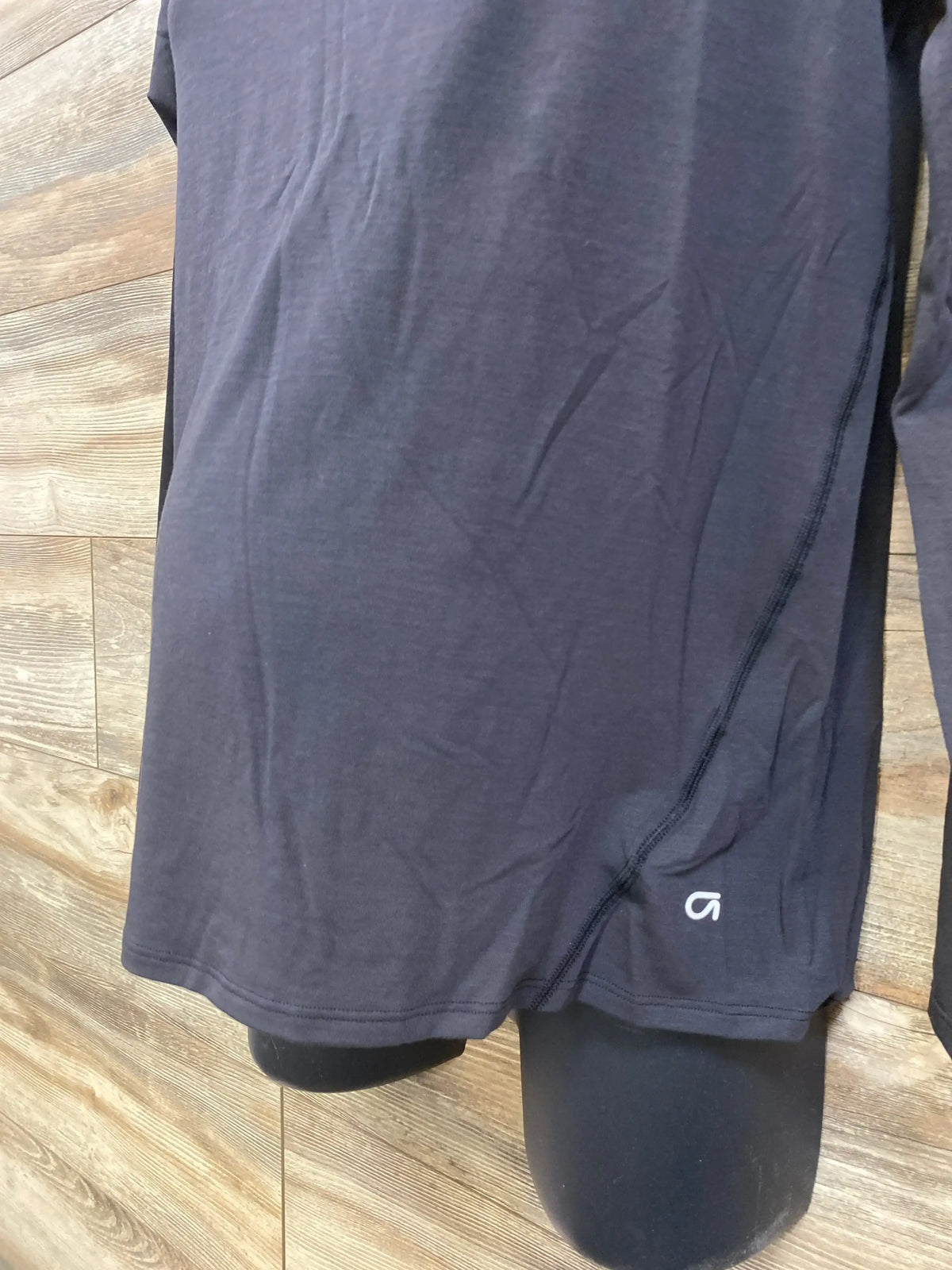 Front view of black Gap maternity long-sleeve Breathe shirt on mannequin showcasing side seam detail and breathable fabric with wood floor background