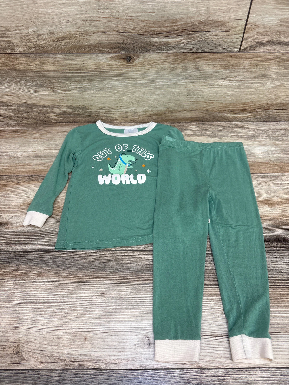 Front view of green Tres Beau et Belle 2pc bamboo dino pajama set with OUT OF THIS WORLD dinosaur graphic and white cuffs