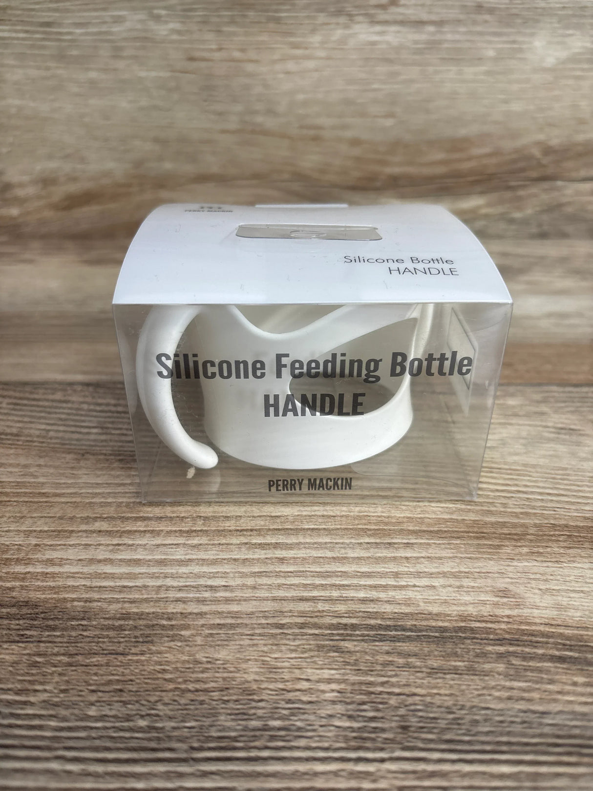 Front view of white silicone bottle handle in clear box showing dual curved handles and packaging text on wood