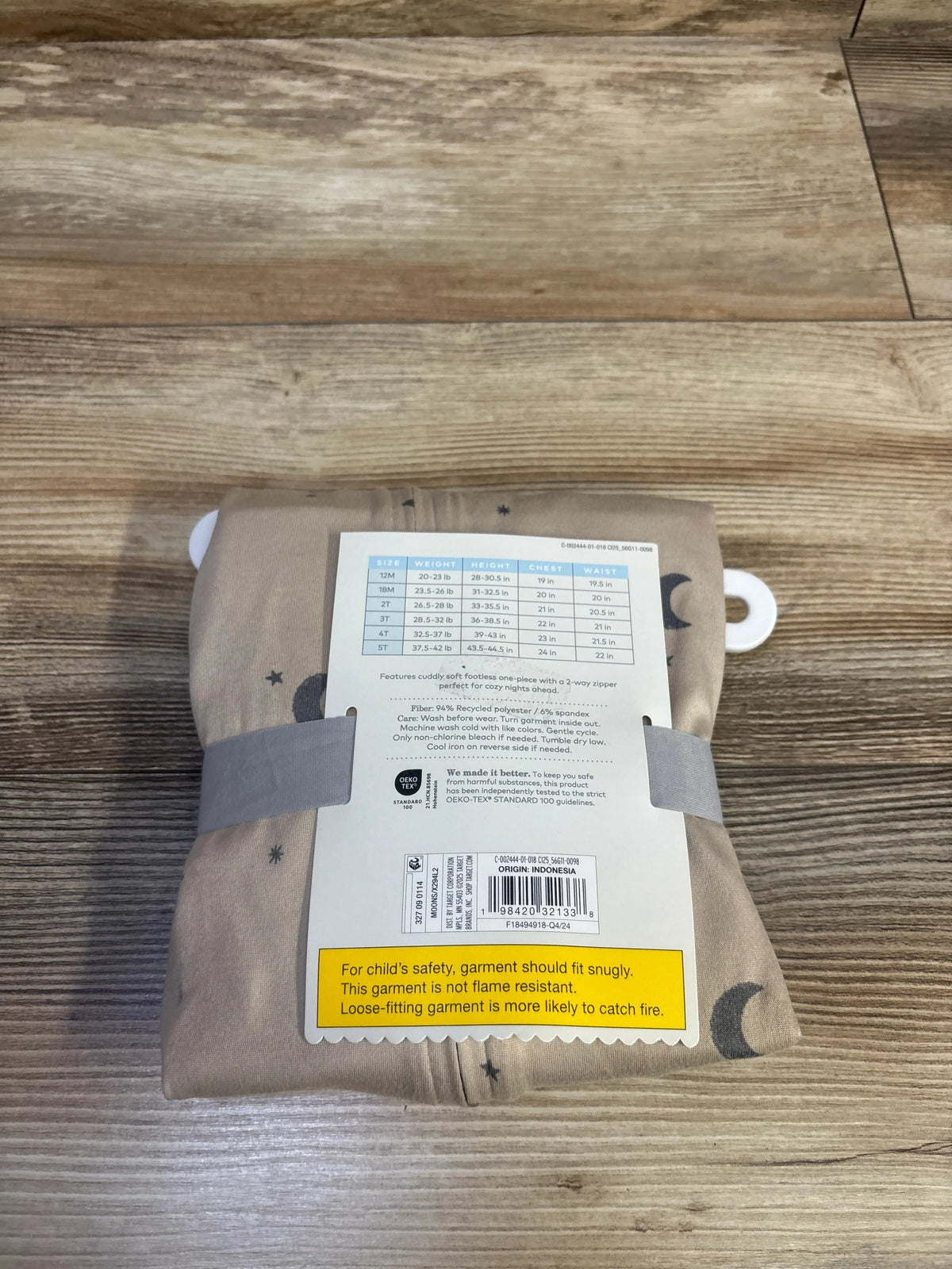 Folded Cloud Island Moon sleeper 5T, tan moon-and-stars print with tag and yellow safety label on wood floor
