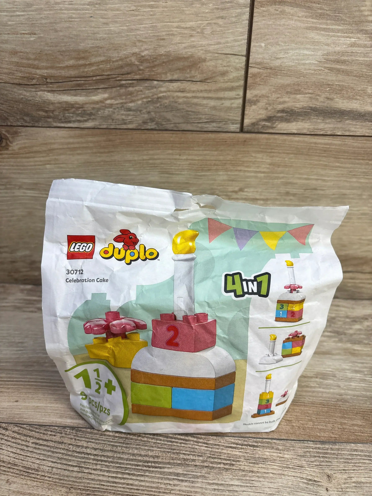 Front view of LEGO DUPLO Celebration Cake packaging showing four build options on a wood floor