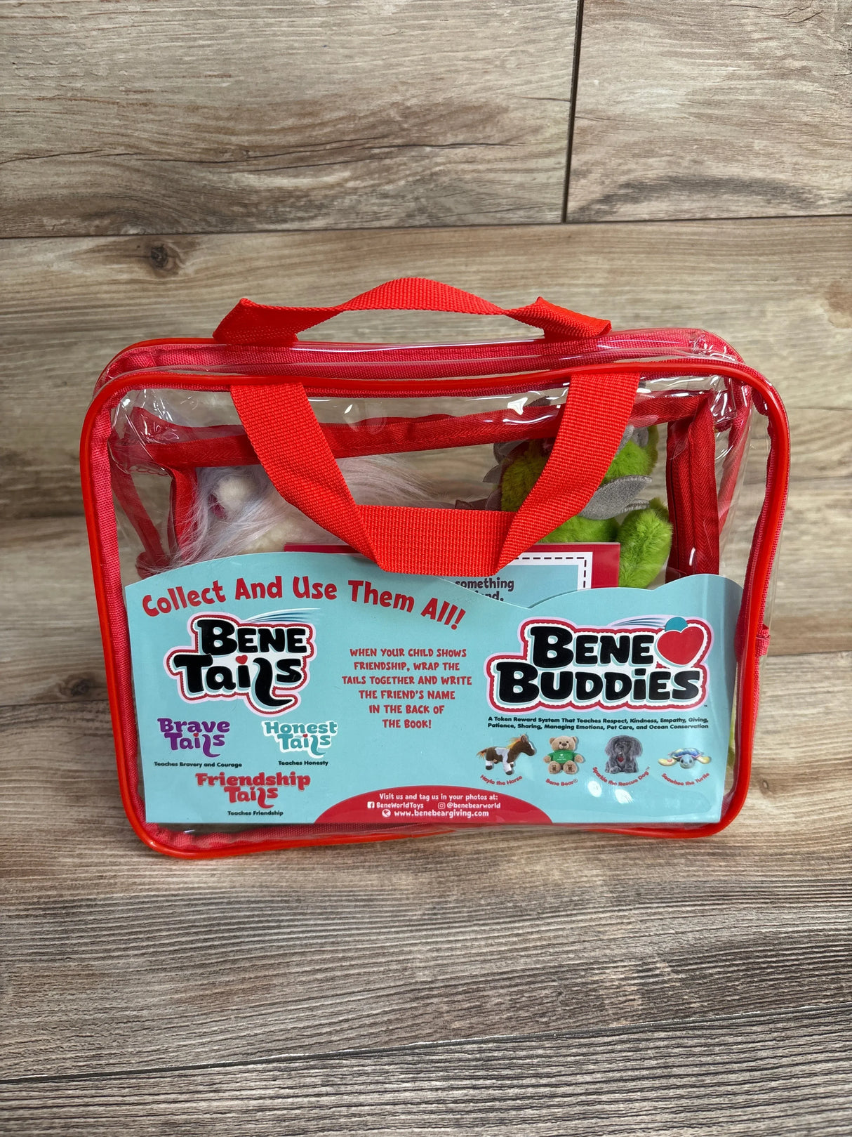 Clear red-handled tote containing Bene Tails Pyro and Uniglo plush set, packaging card reads Collect And Use Them All on wood surface