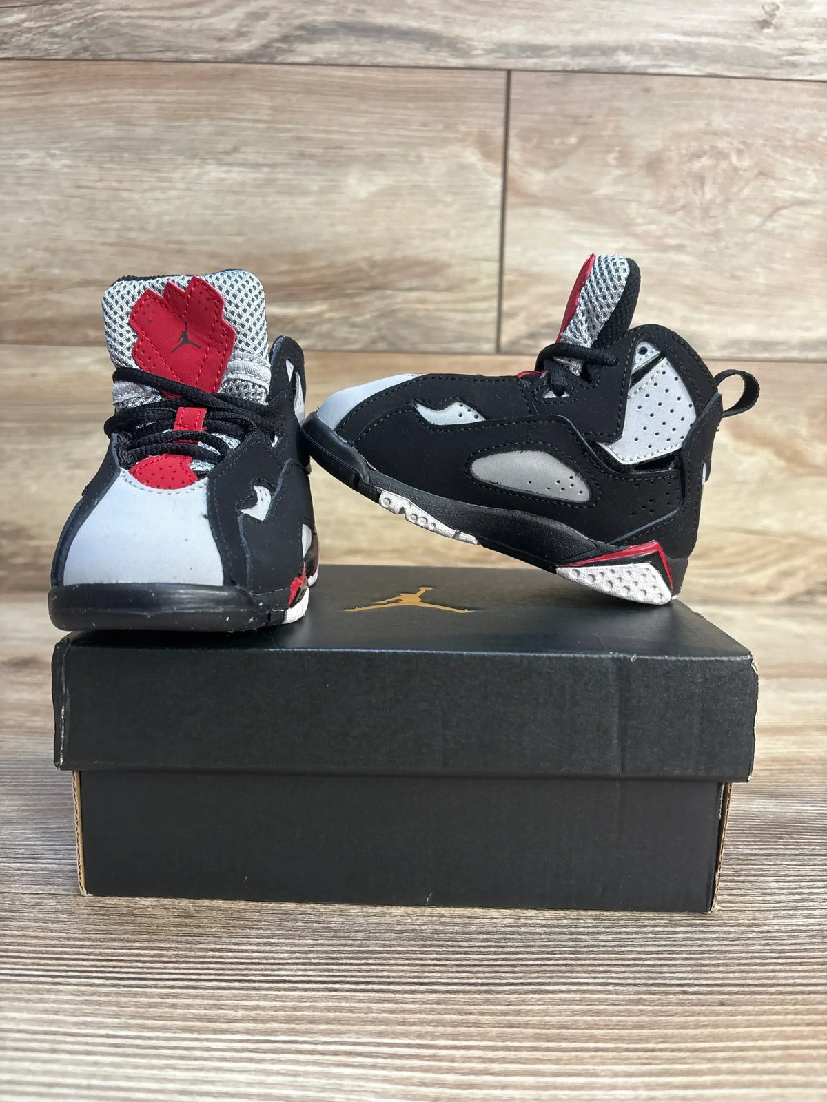Toddler black and gray athletic sneakers with red accents displayed on a shoebox
