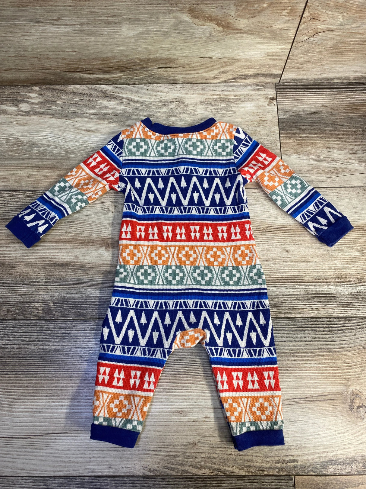Colorful patterned baby romper with geometric shapes on wooden floor