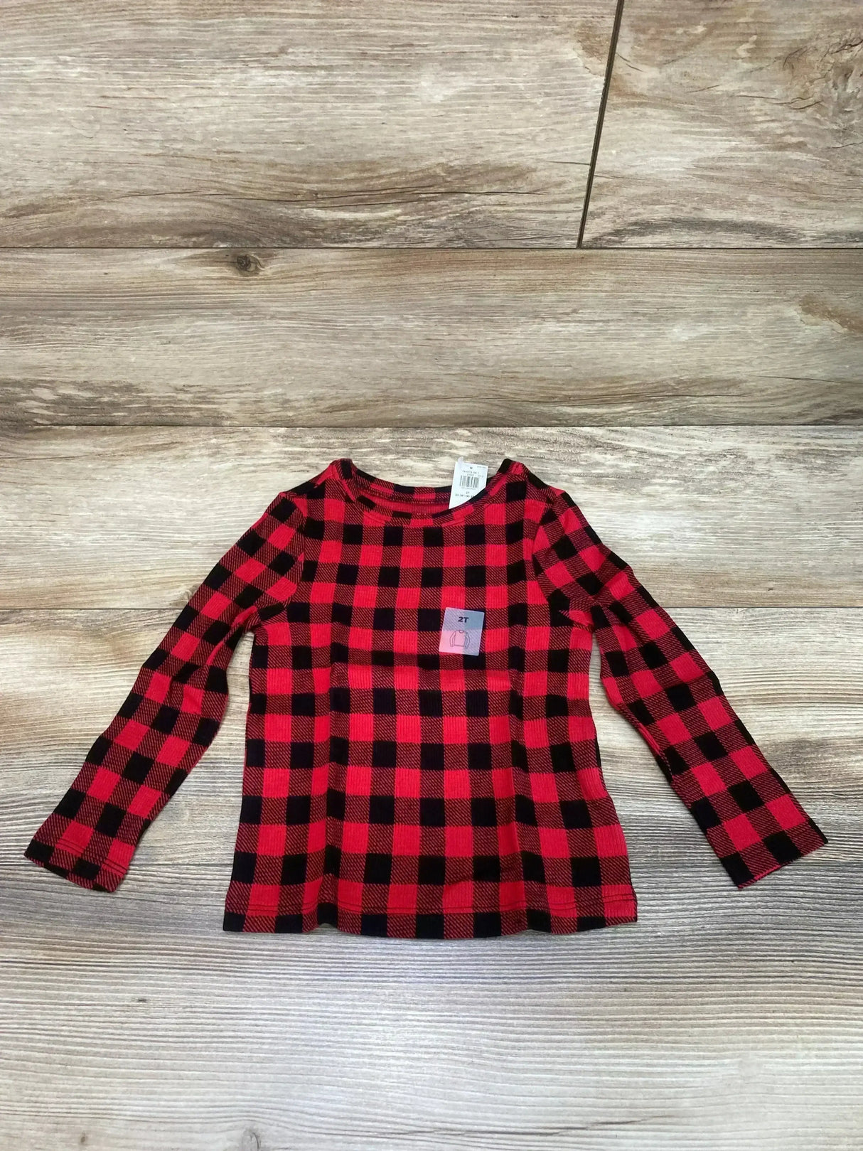 Flat lay of toddler Old Navy red and black buffalo check long-sleeve shirt with visible size sticker on wood background