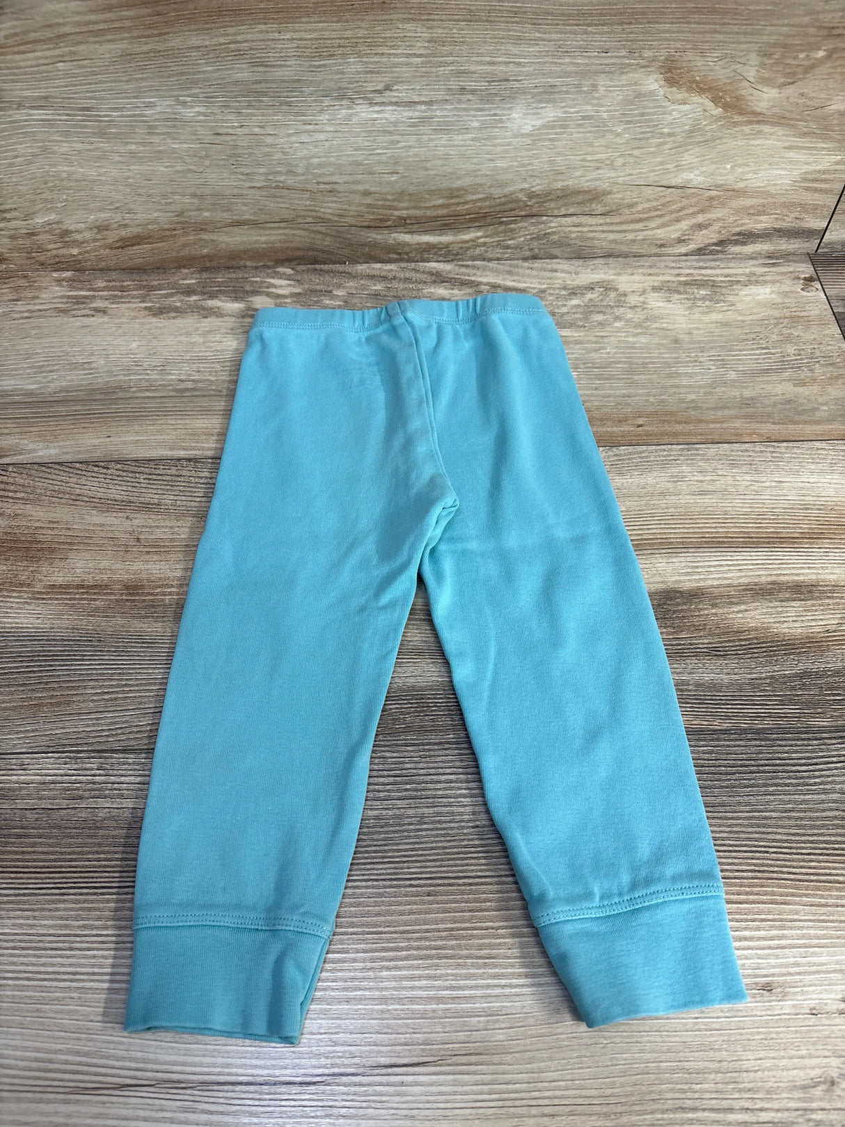Light blue baby leggings on a wooden background