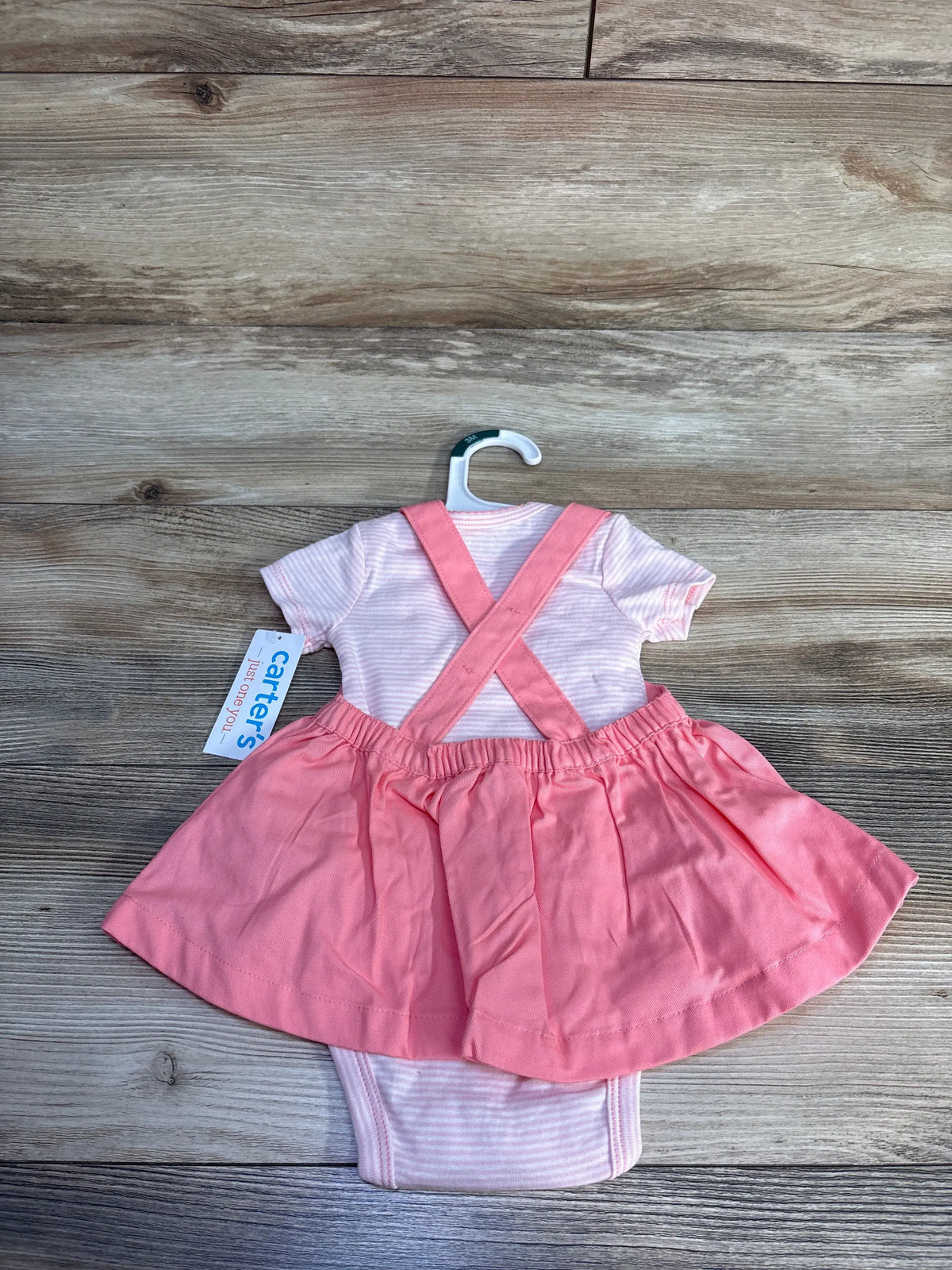 Flat lay of pink watermelon-themed skirtall and bodysuit set showcasing crossed straps and striped fabric