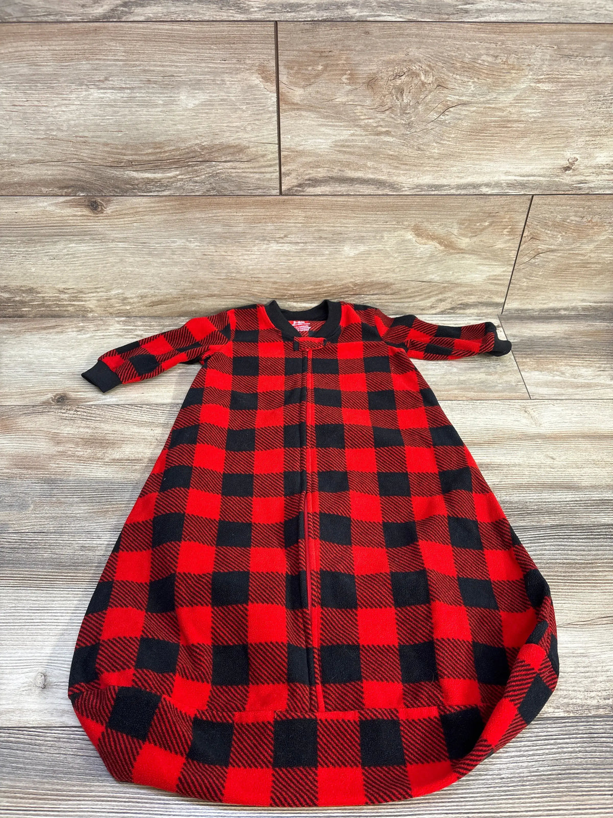 Top view of Carter’s red and black plaid sleep sack with front zipper, long sleeves, and roomy bottom on wood floor