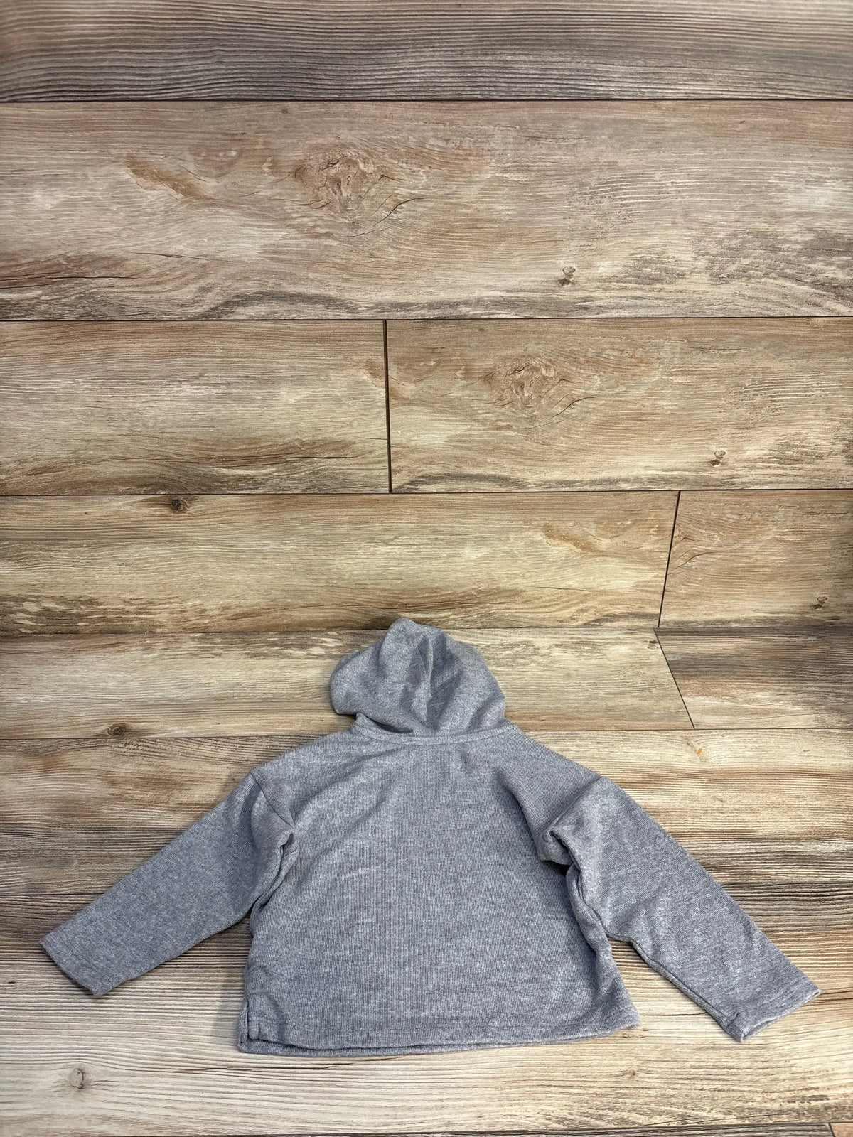Back view of Easy Peasy grey hooded shirt showcasing its hood and long sleeves on a wood plank background