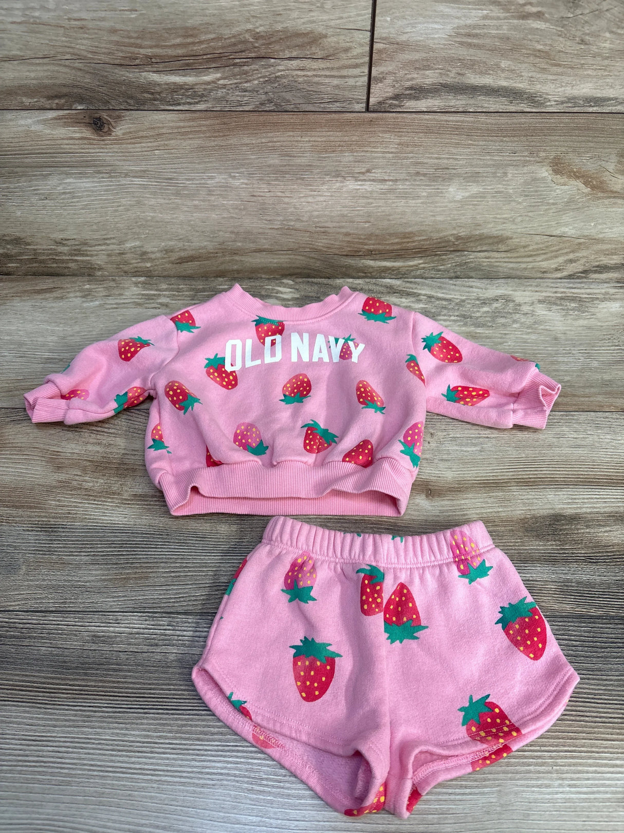 Toddler pink Old Navy sweatshirt and shorts set with strawberry print on wooden floor