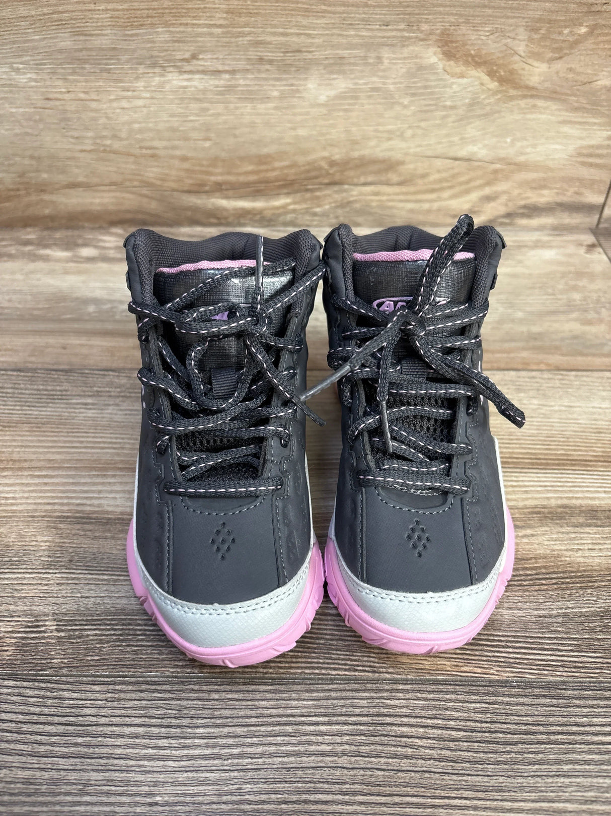 Pair of black and pink toddler hiking boots with laces on wooden surface