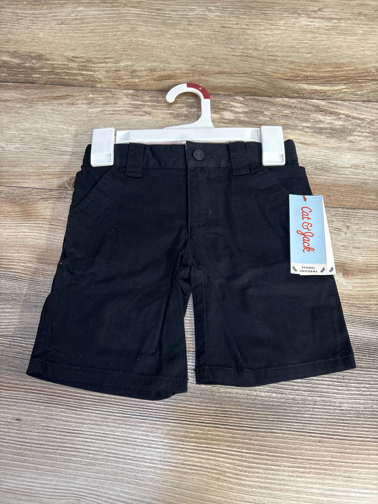 Front view of Cat and Jack black toddler uniform shorts, size 4T, showing belt loops and side pockets on wood background