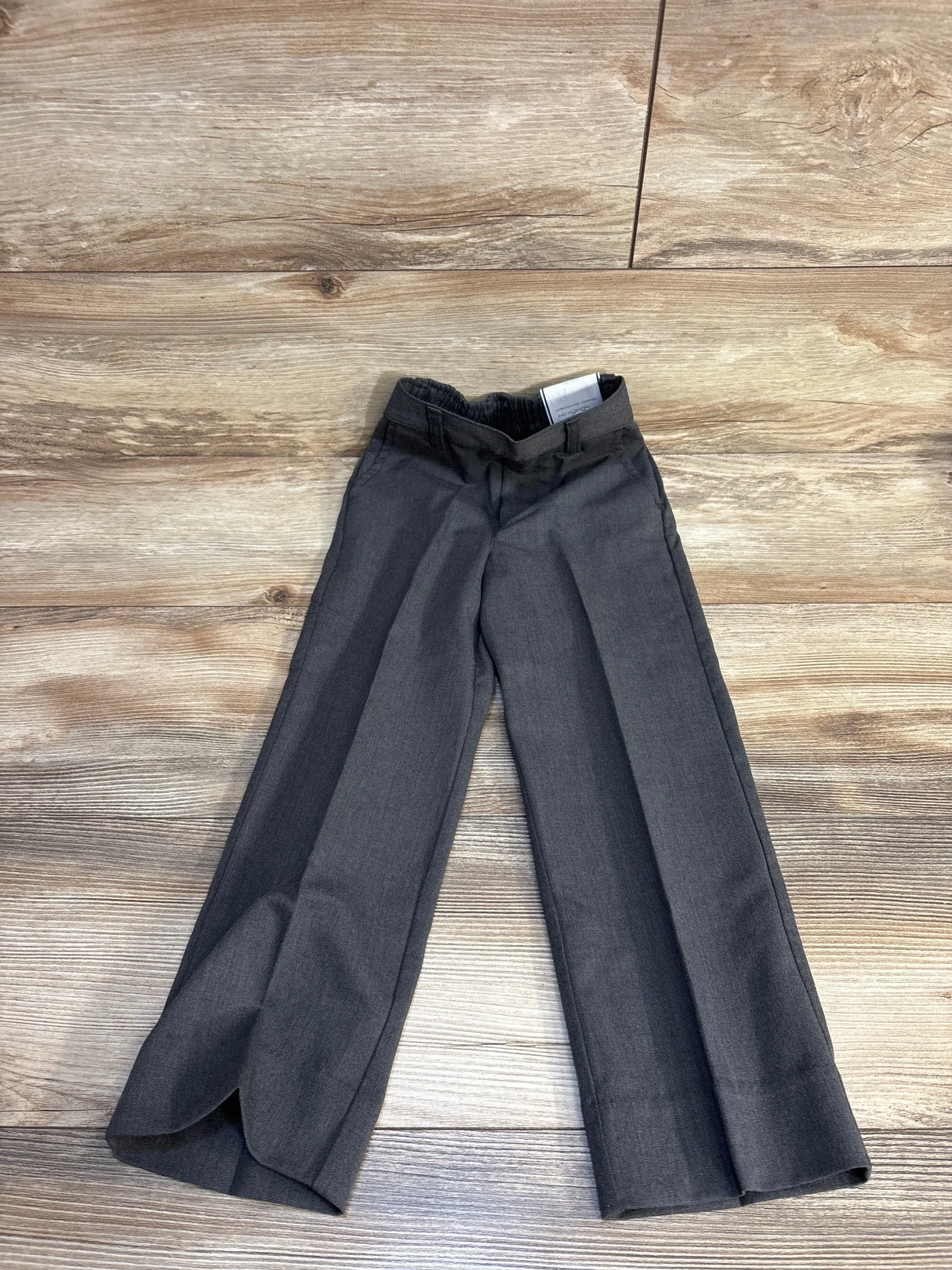 Gray kids' stretch pants with elastic waist, laid flat on wood floor for resale