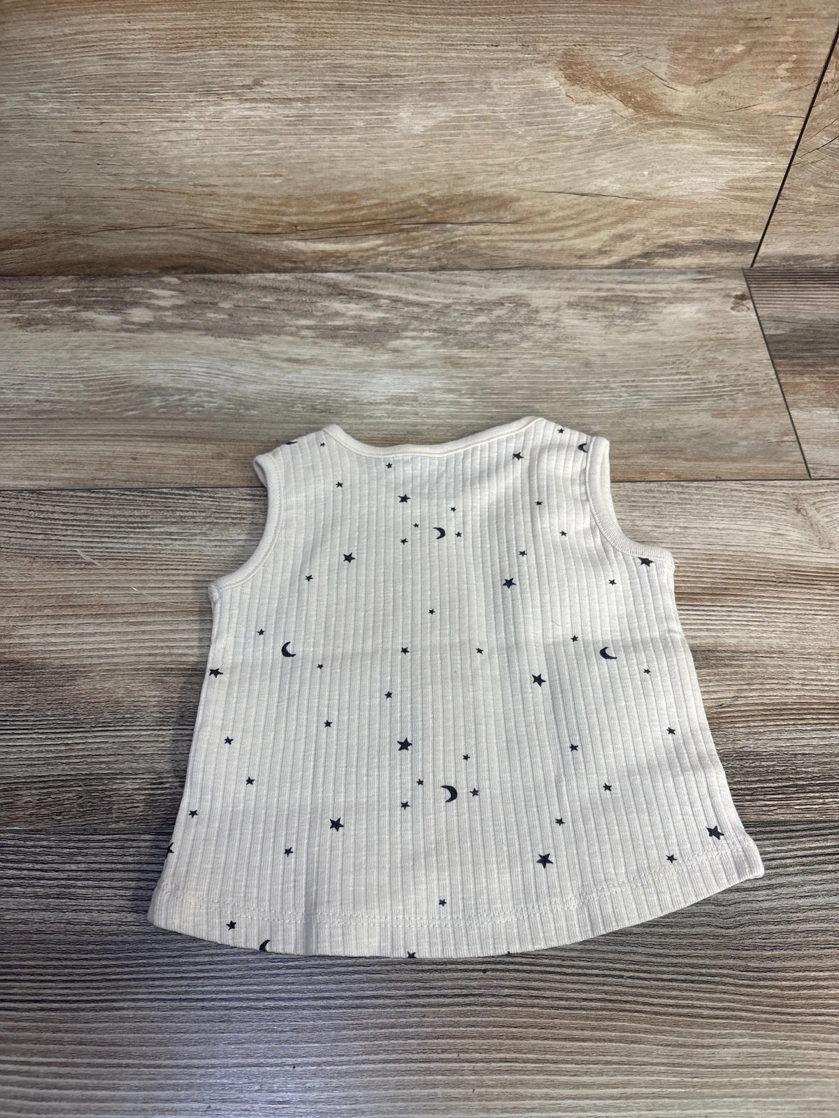 Front view of Modern Moments ribbed tank top in beige, showcasing organic cotton fabric with star and crescent moon pattern on wood floor