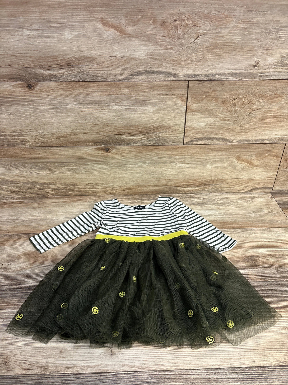 Girls black and white striped dress with yellow waistband and tulle skirt on wood floor