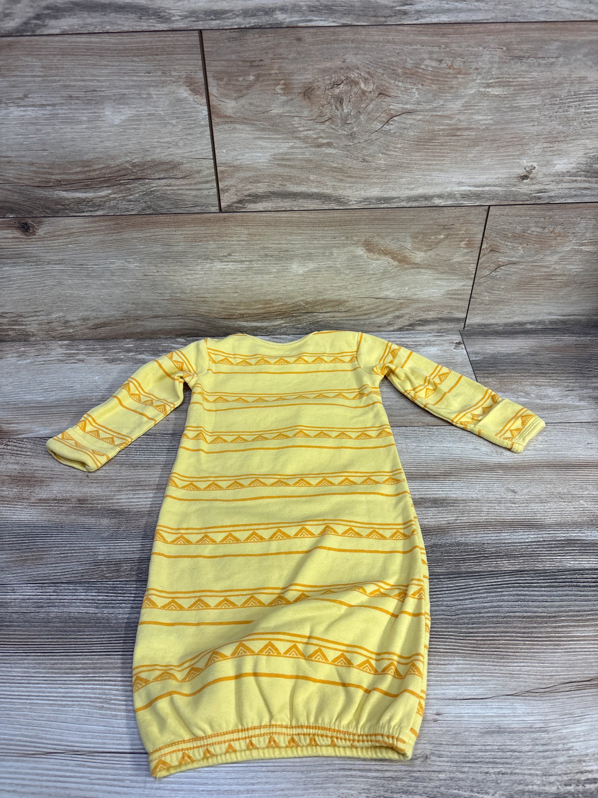Flat lay of yellow Disney Baby Lion King sleep gown showcasing long sleeves and elastic bottom on wood floor