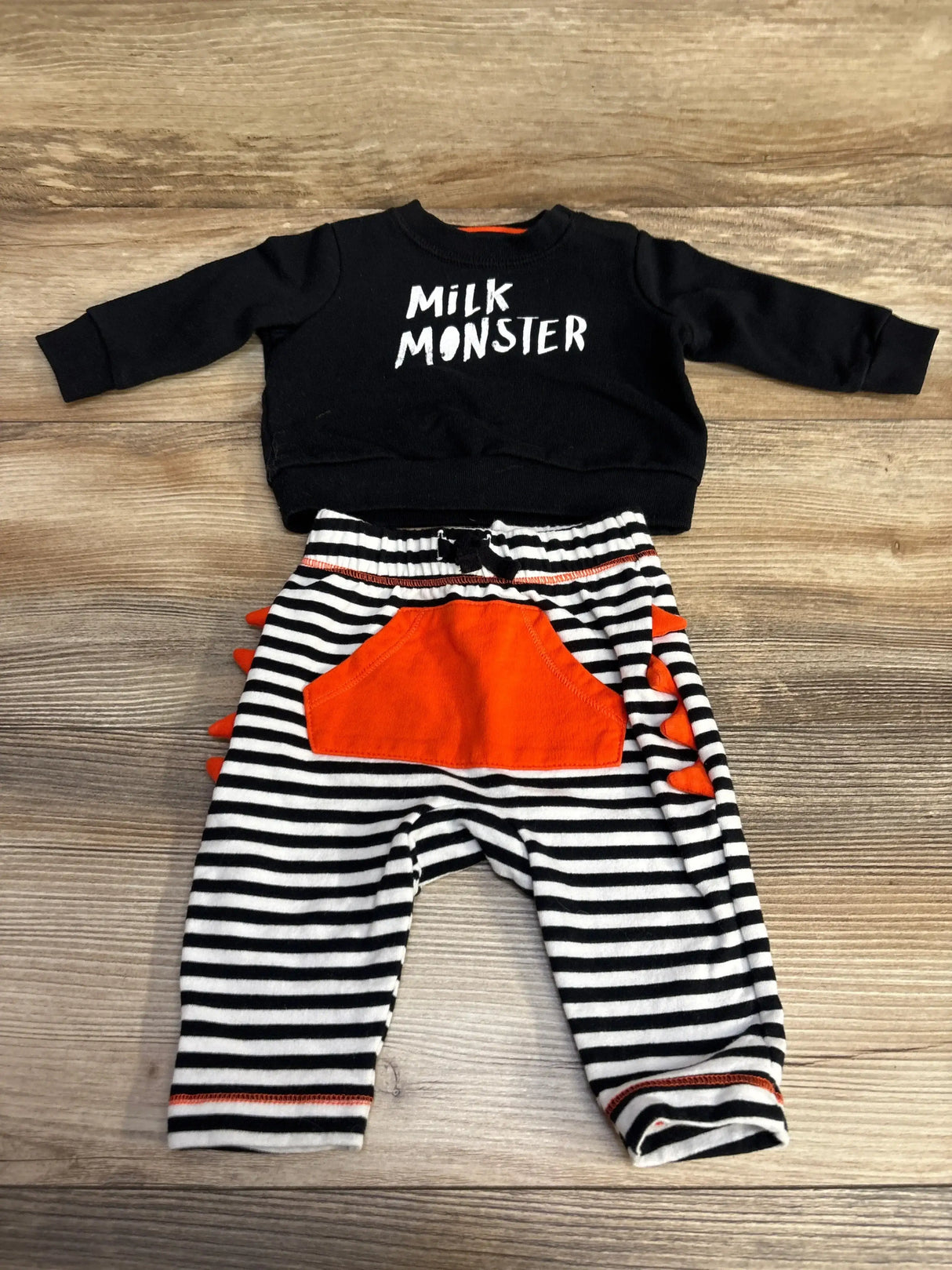 Front view of Cat & Jack Milk Monster sweatshirt and joggers set showcasing striped pants and orange pocket on wood floor