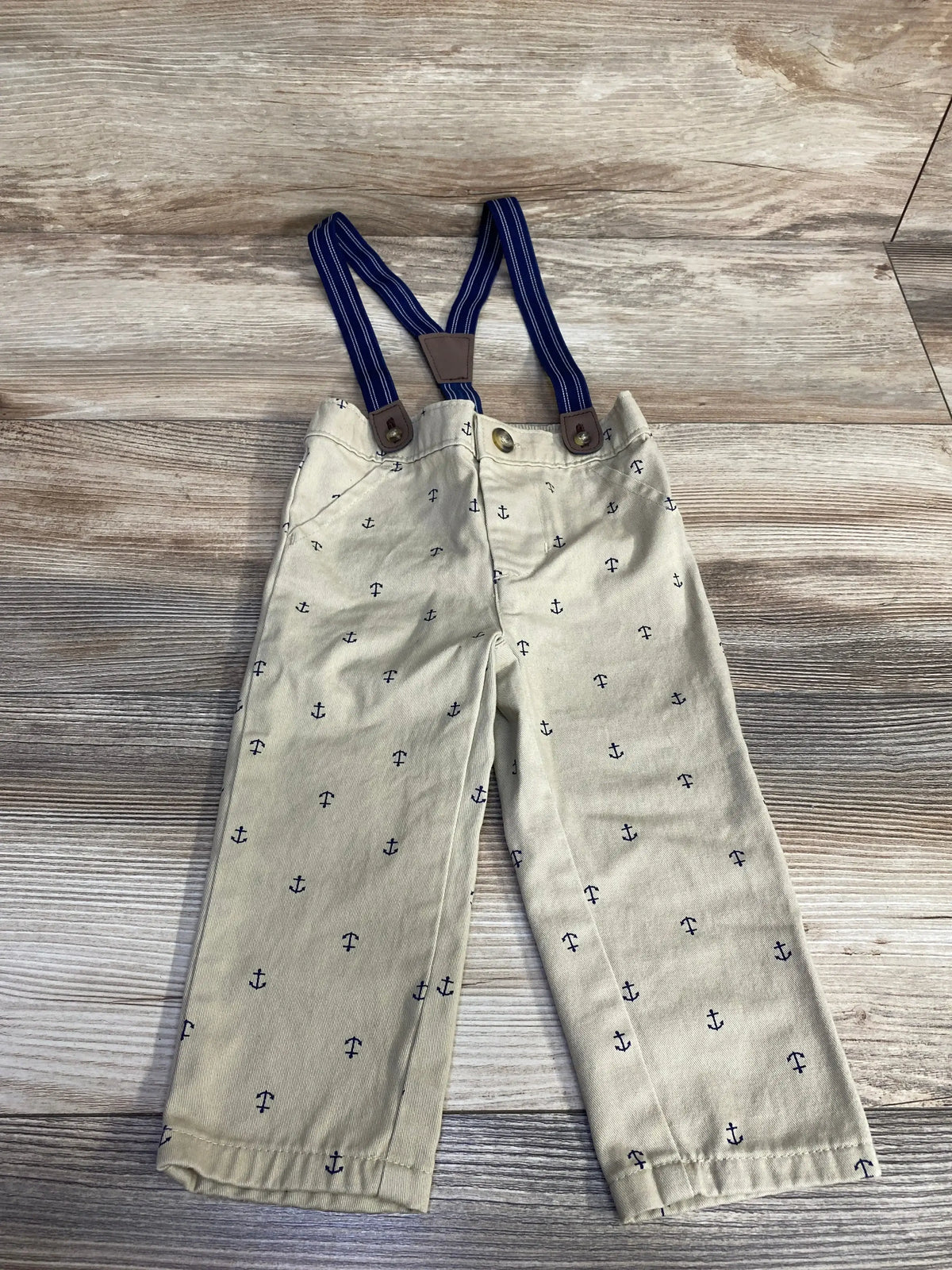 Front view of tan suspender pants with navy anchor print and adjustable straps, size 12 months on white background