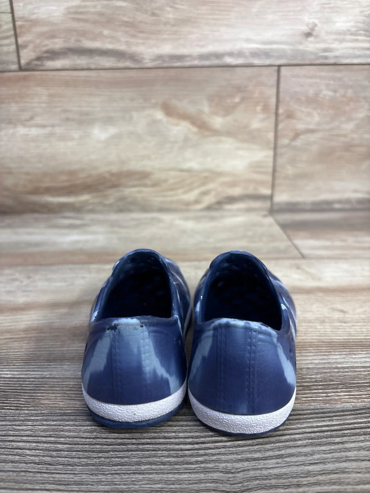 Rear view of Cat & Jack toddler blue slip-on water shoes showing tie-dye pattern and white textured sole on wood floor