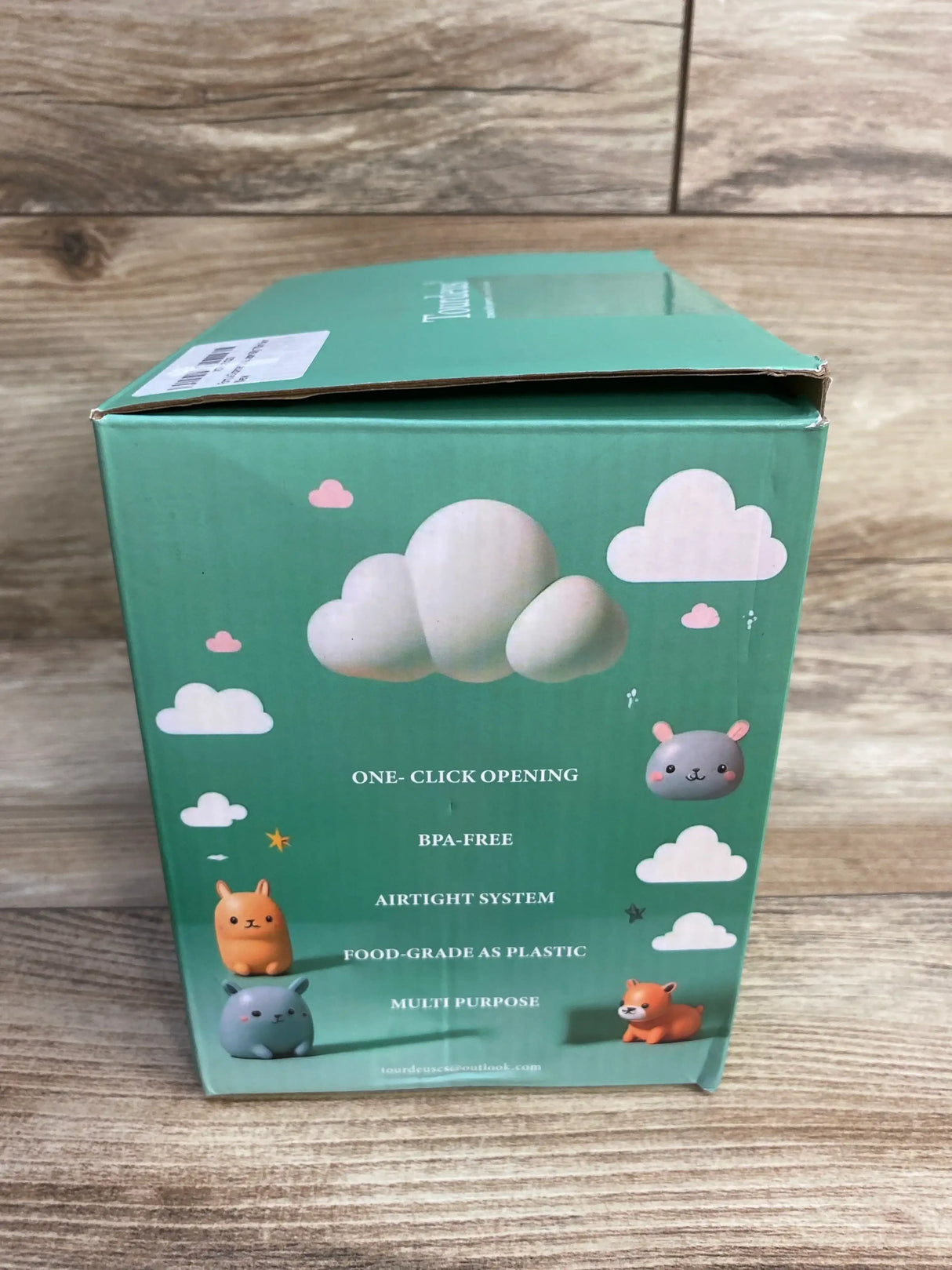 Side of Ankou formula container green box listing one click opening BPA free airtight system food grade plastic features on wood plank floor