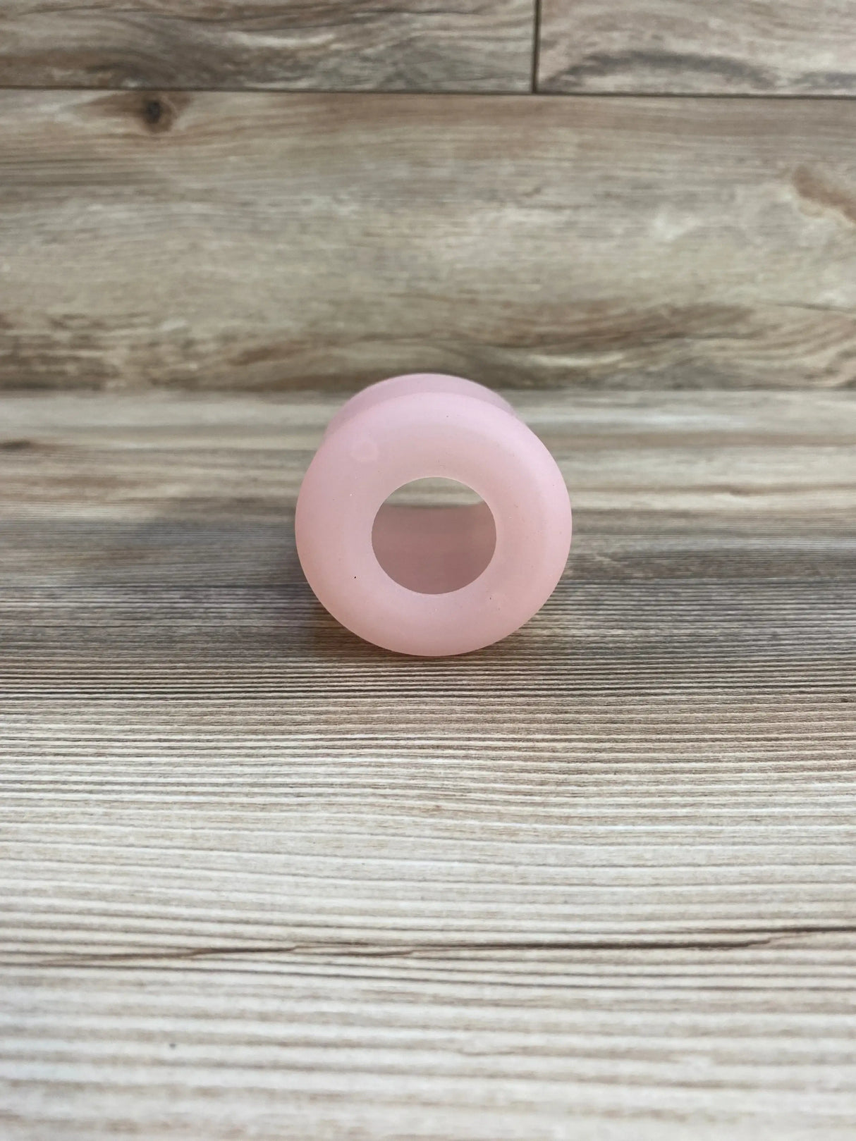 Front view of Dr Brown’s narrow 100% silicone 8oz baby bottle sleeve showcasing the open circular end and pink color on a wood surface