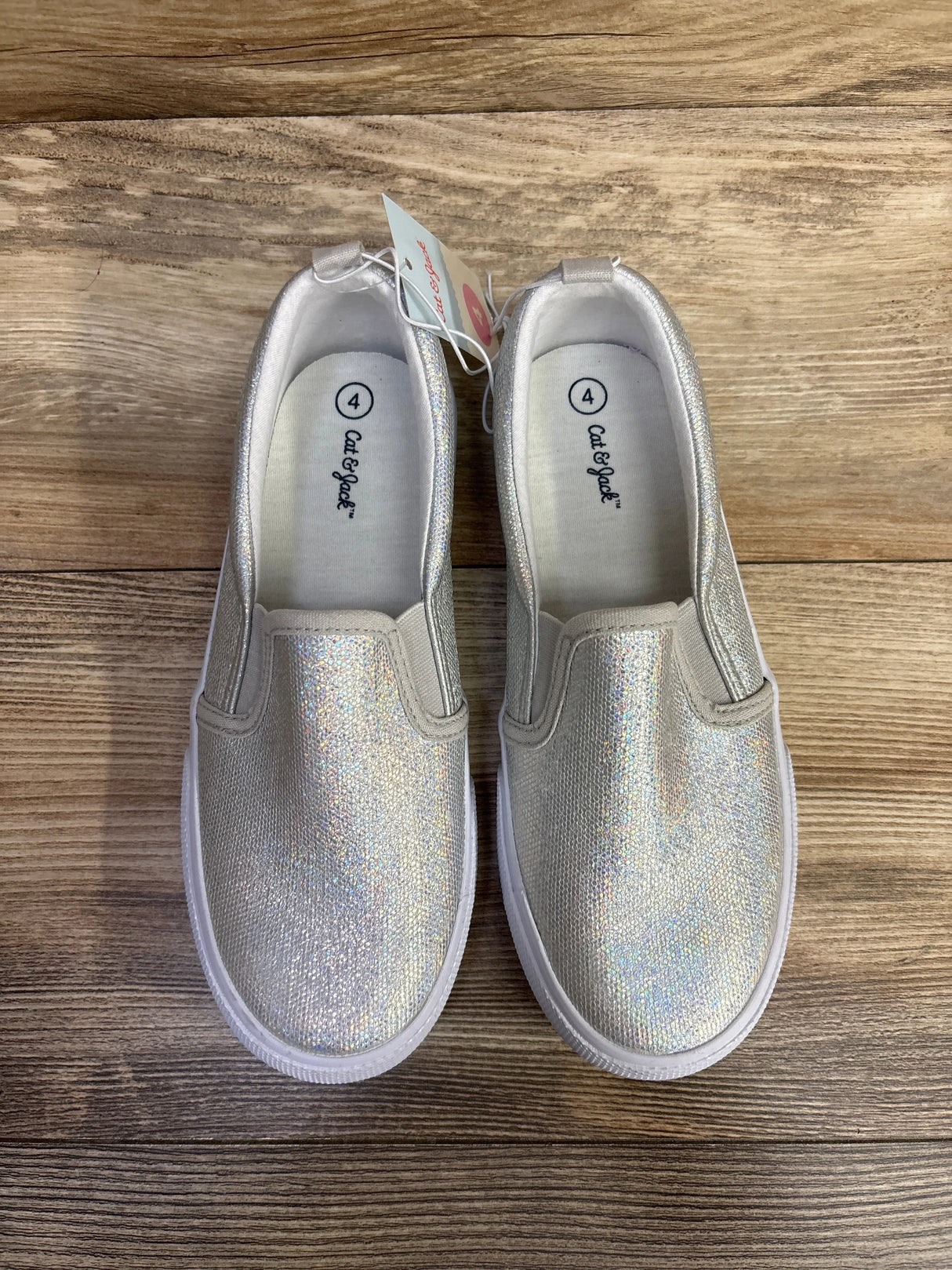 Pair of size 4 Cat & Jack glittery silver slip-on kids sneakers on wooden floor