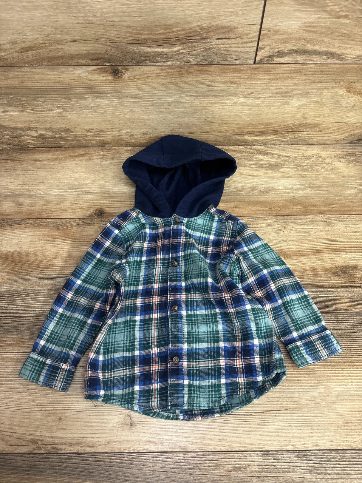 Plaid flannel button-up toddler shirt with navy hood on wood background