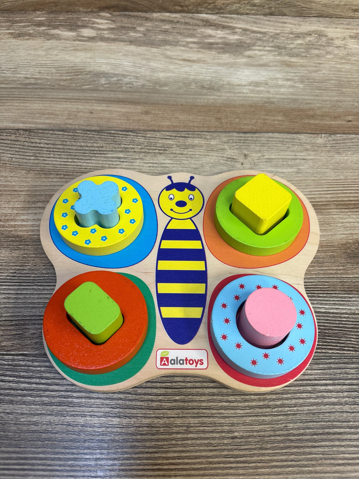 Top view of Aalatoys butterfly wooden shape sorting puzzle (9 pieces) showing four stacked rings and four shapes on wood