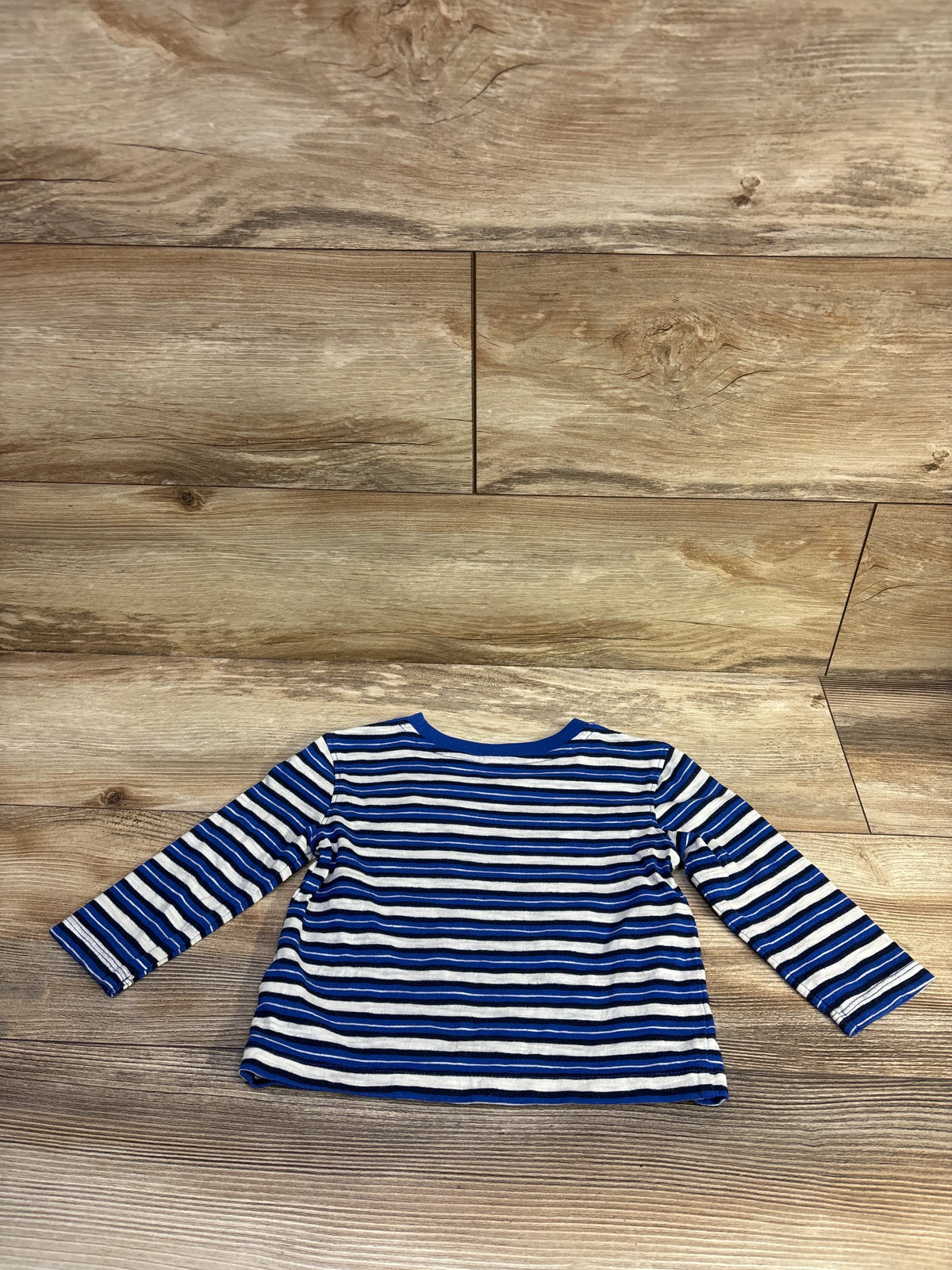 Front view of Old Navy blue striped pocket shirt with long sleeves for ages 12 to 18 months on a wood-grain background