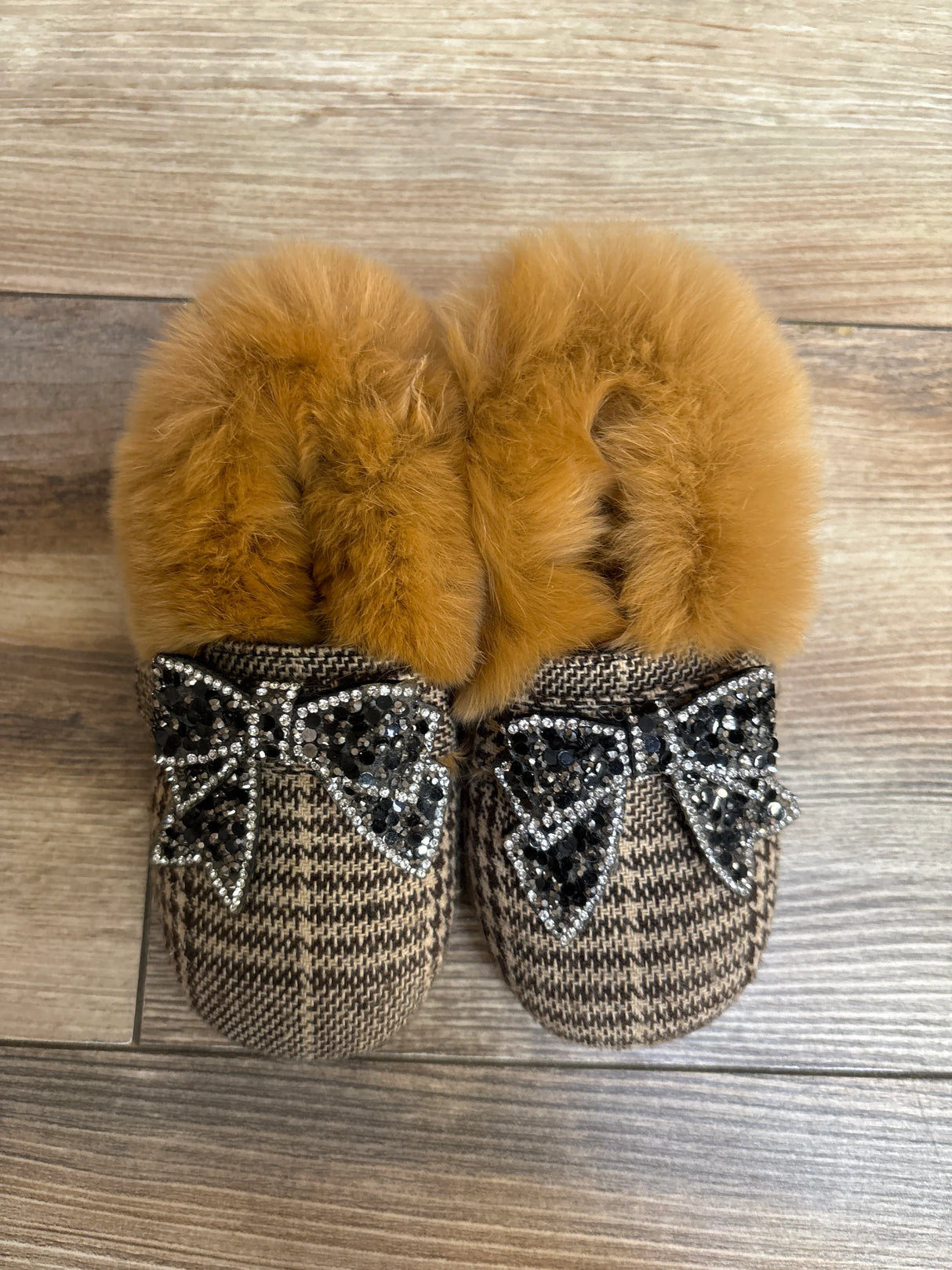 Plaid fur-lined slippers with jeweled bow accents on wood floor