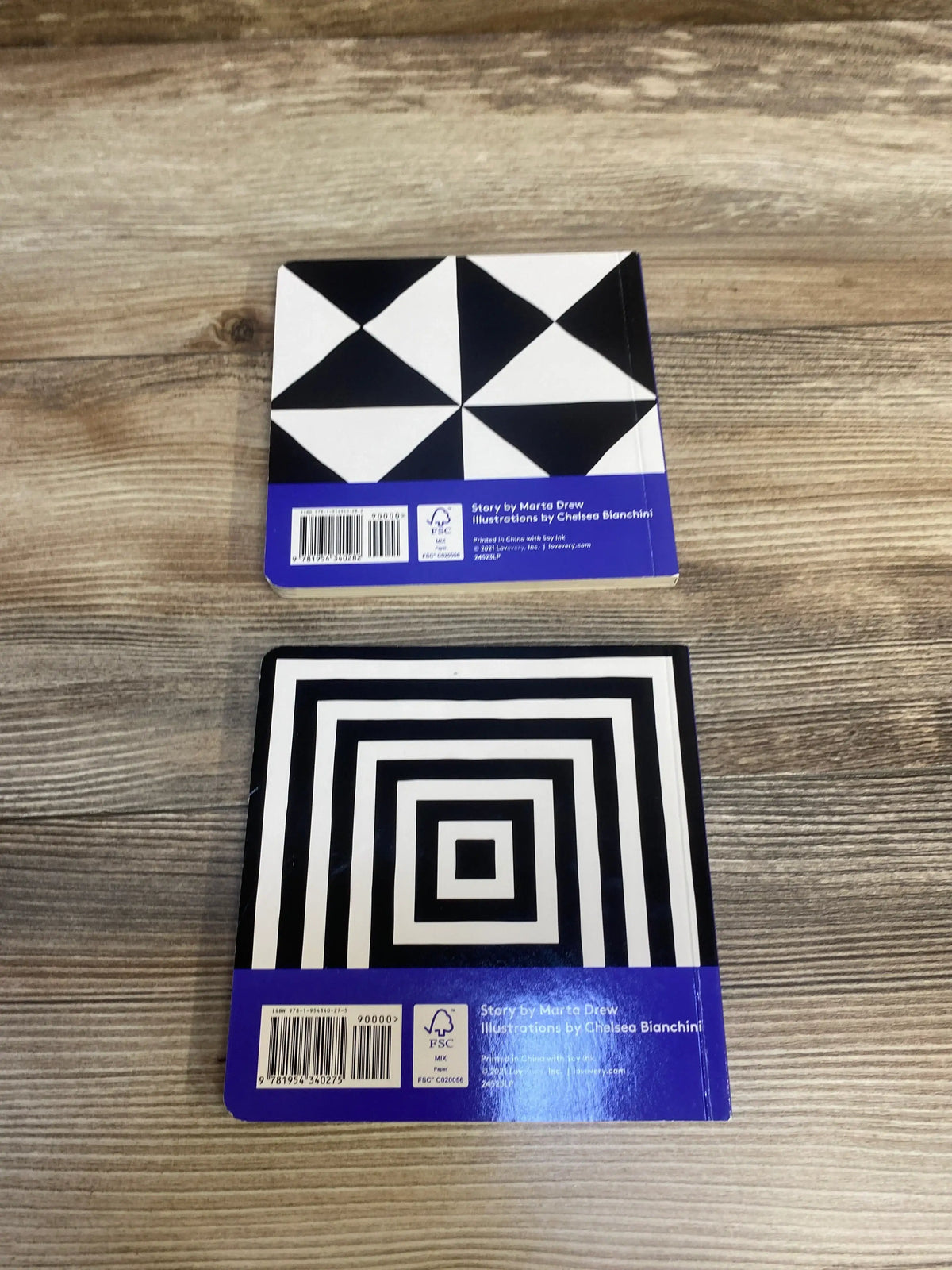 Two board books for babies with high contrast black and white geometric designs on wood surface