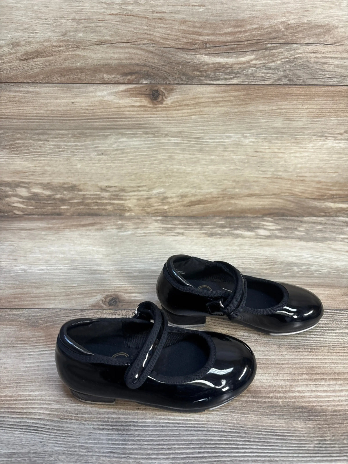Black patent leather Mary Jane toddler shoes with strap on wood background