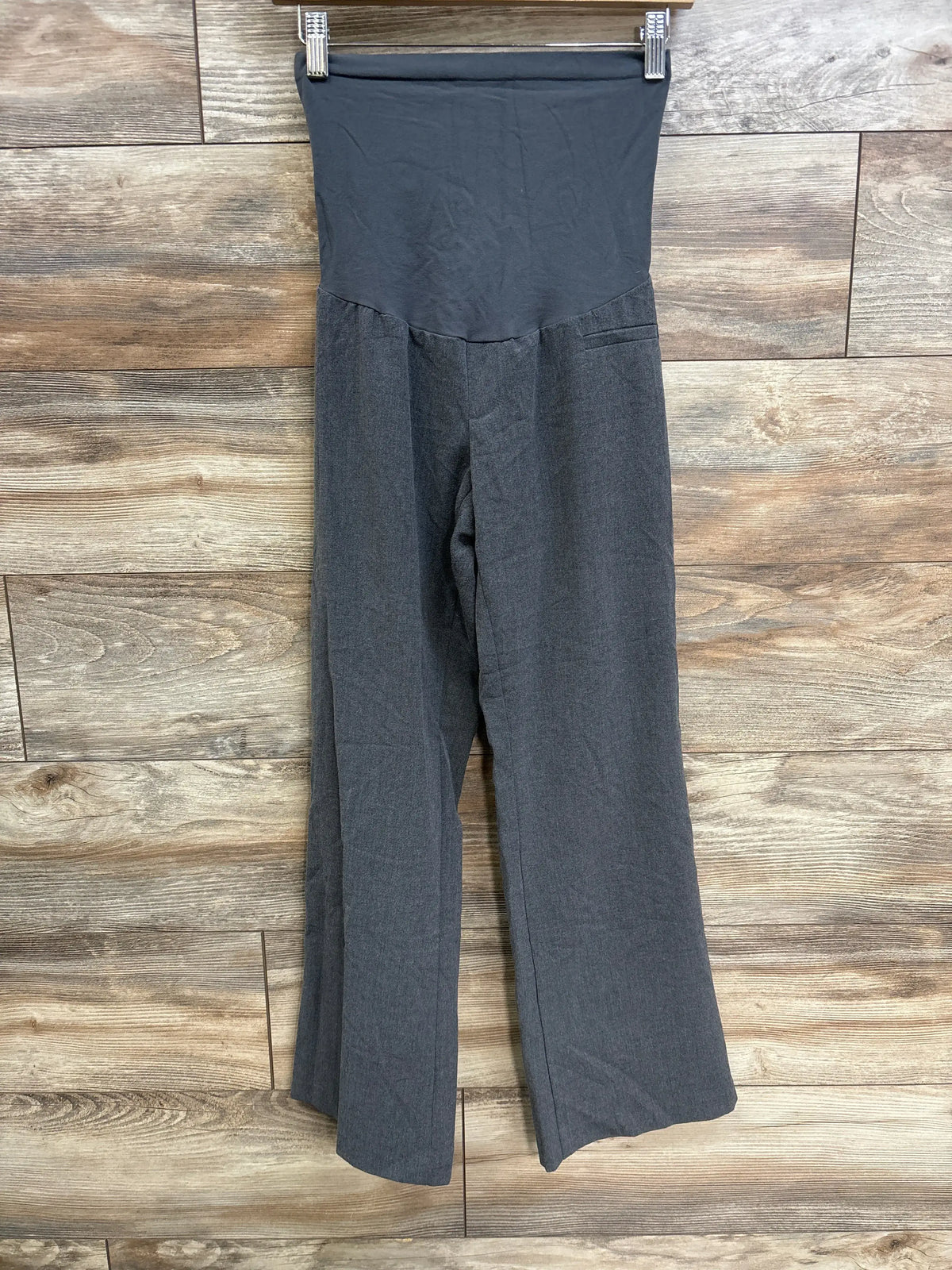 Front view of gray Motherhood Maternity pants in petite medium, showing full panel waistband, wide legs, and pocket on wood