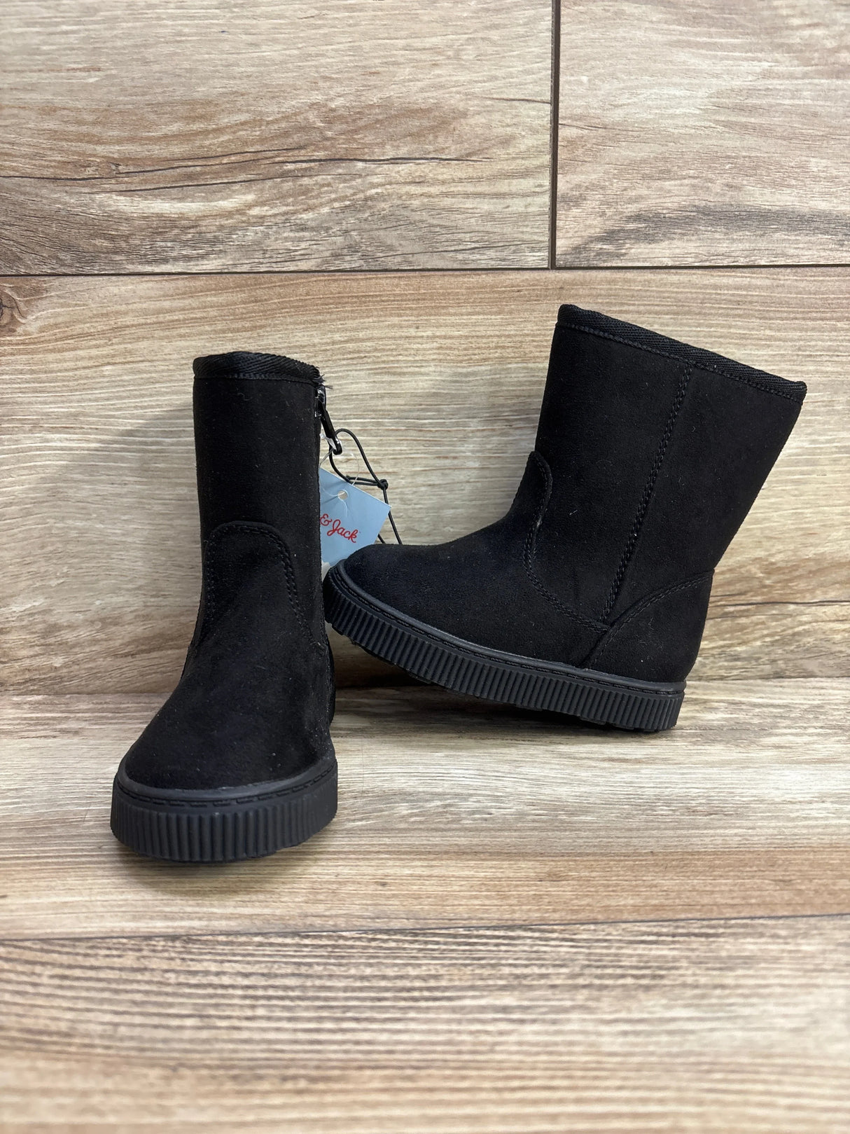 Black suede kids ankle boots with side zipper on wood background