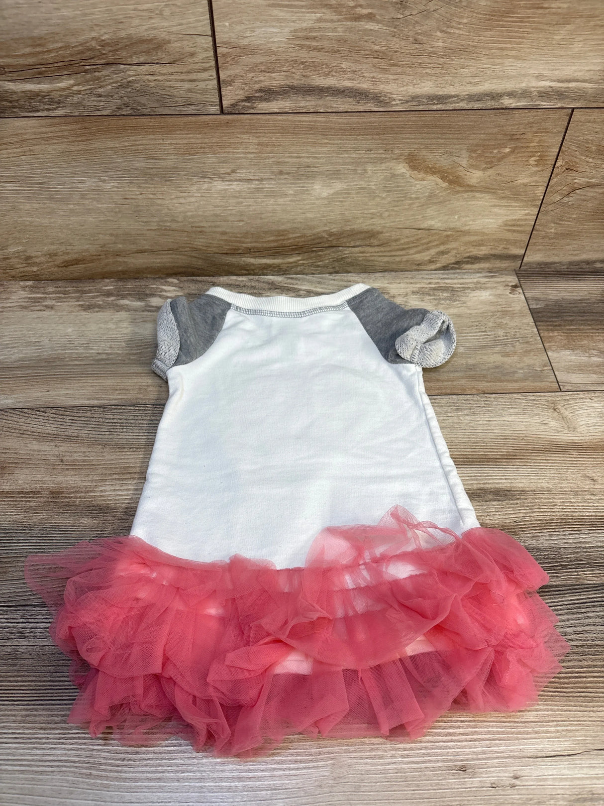 Flat lay of Bonnie Jean textured tulle sweatshirt dress, grey with layered pink ruffle tulle skirt on wood background