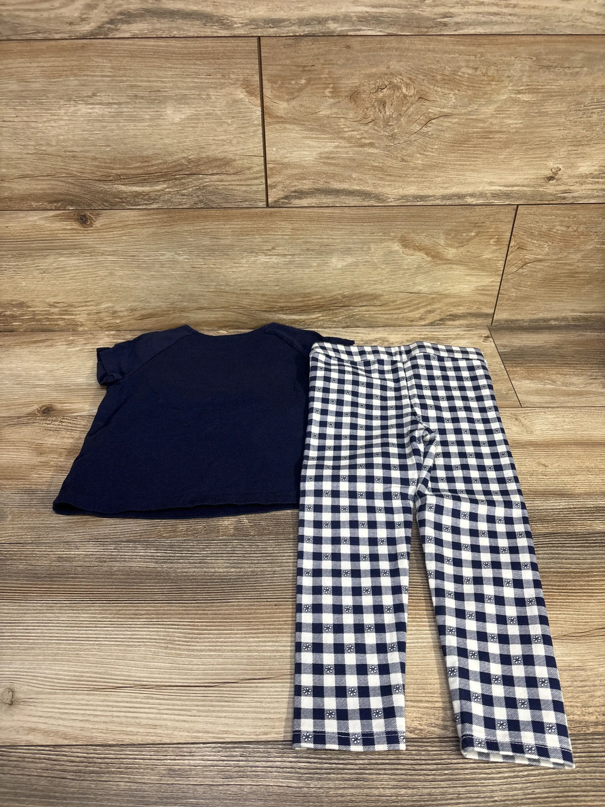 Flat lay of Janie & Jack 2-piece toddler outfit showcasing a navy top and gingham pants with button details